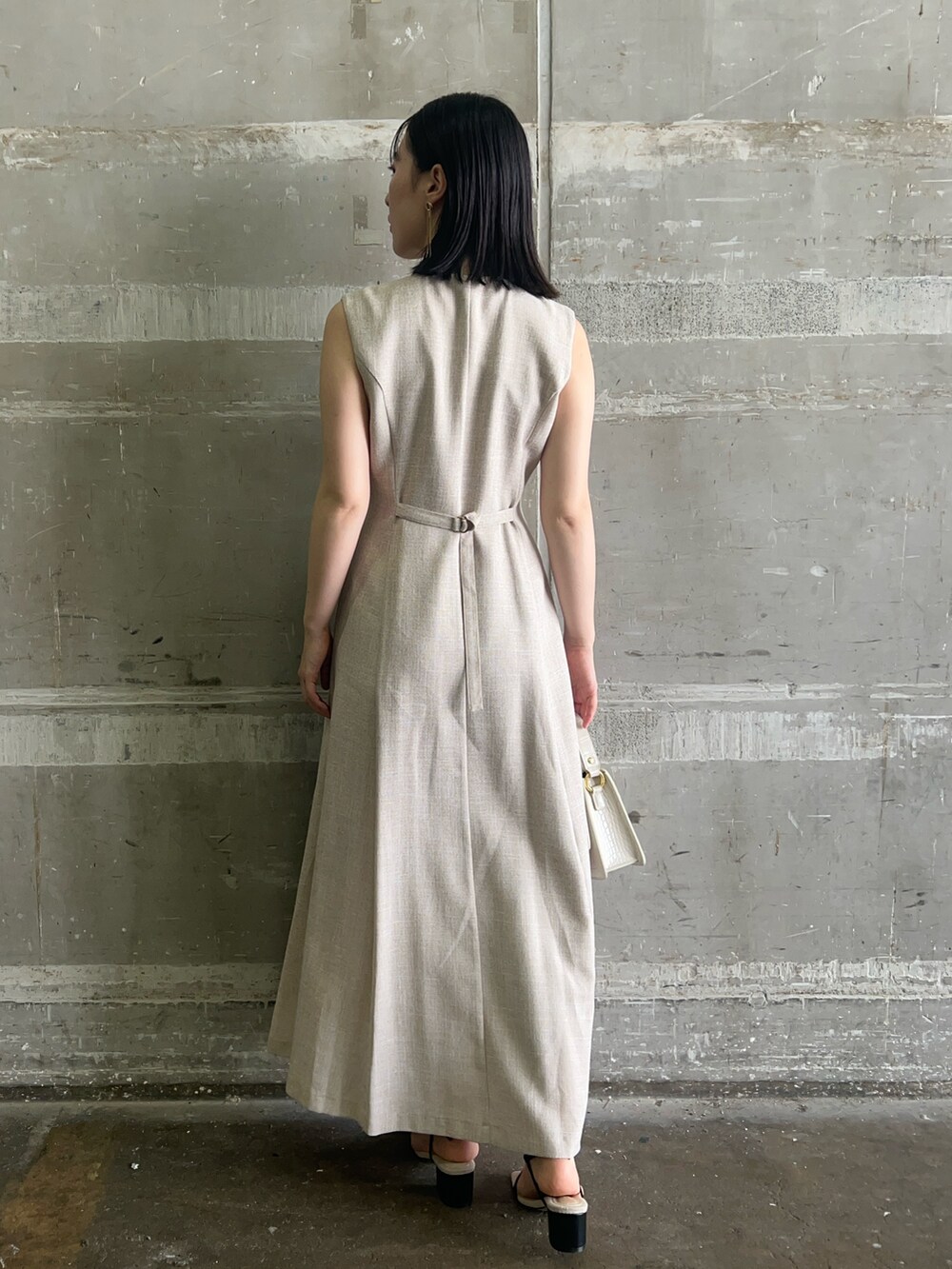 ブラック系のサンダル、ホワイト系のショルダーバッグ、ベージュ系のワンピースを着用したレディースの夏コーディネートの3枚目の写真