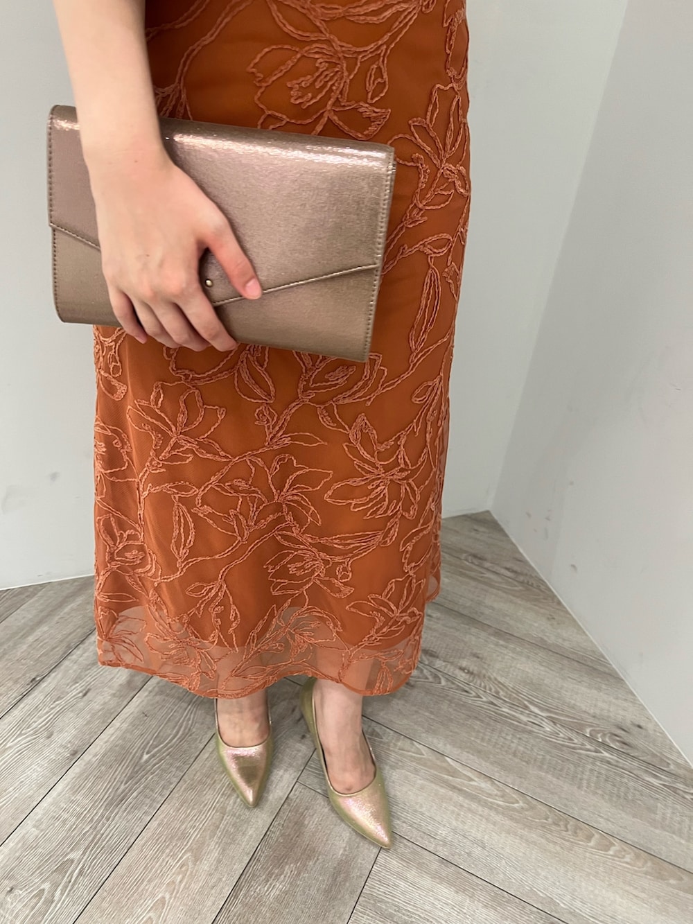 ゴールド系のパンプス、ゴールド系のハンドバッグ、オレンジ系のドレスを着用したレディースの夏コーディネートの8枚目の写真