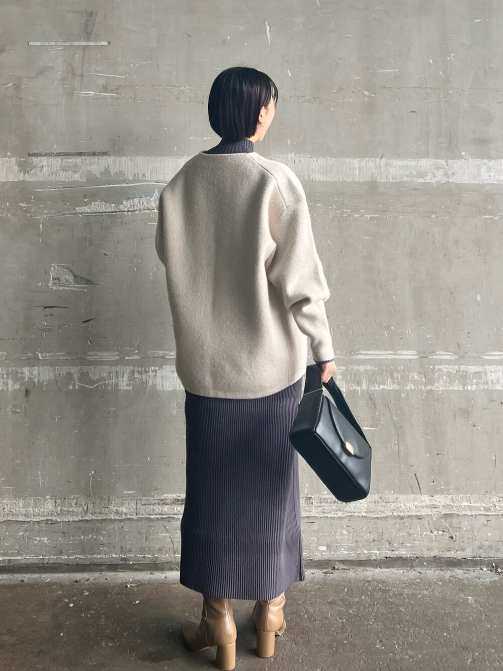 ブラック系のハンドバッグ、ベージュ系のブーツ、ホワイト系のカーディガン/ボレロを着用したレディースの冬コーディネートの2枚目の写真