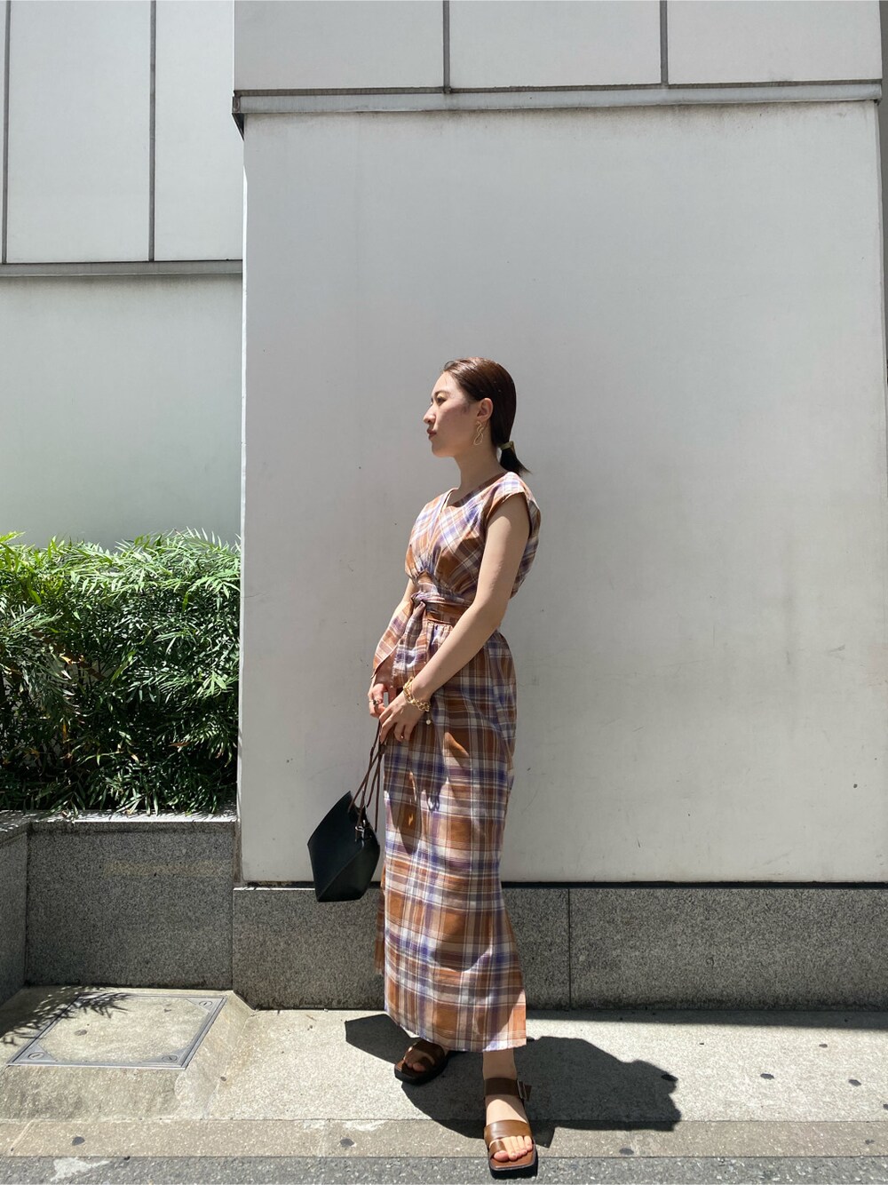 ブラック系のハンドバッグ、ブラウン系のサンダル、ブラウン系のワンピースを着用したレディースの夏コーディネートの2枚目の写真