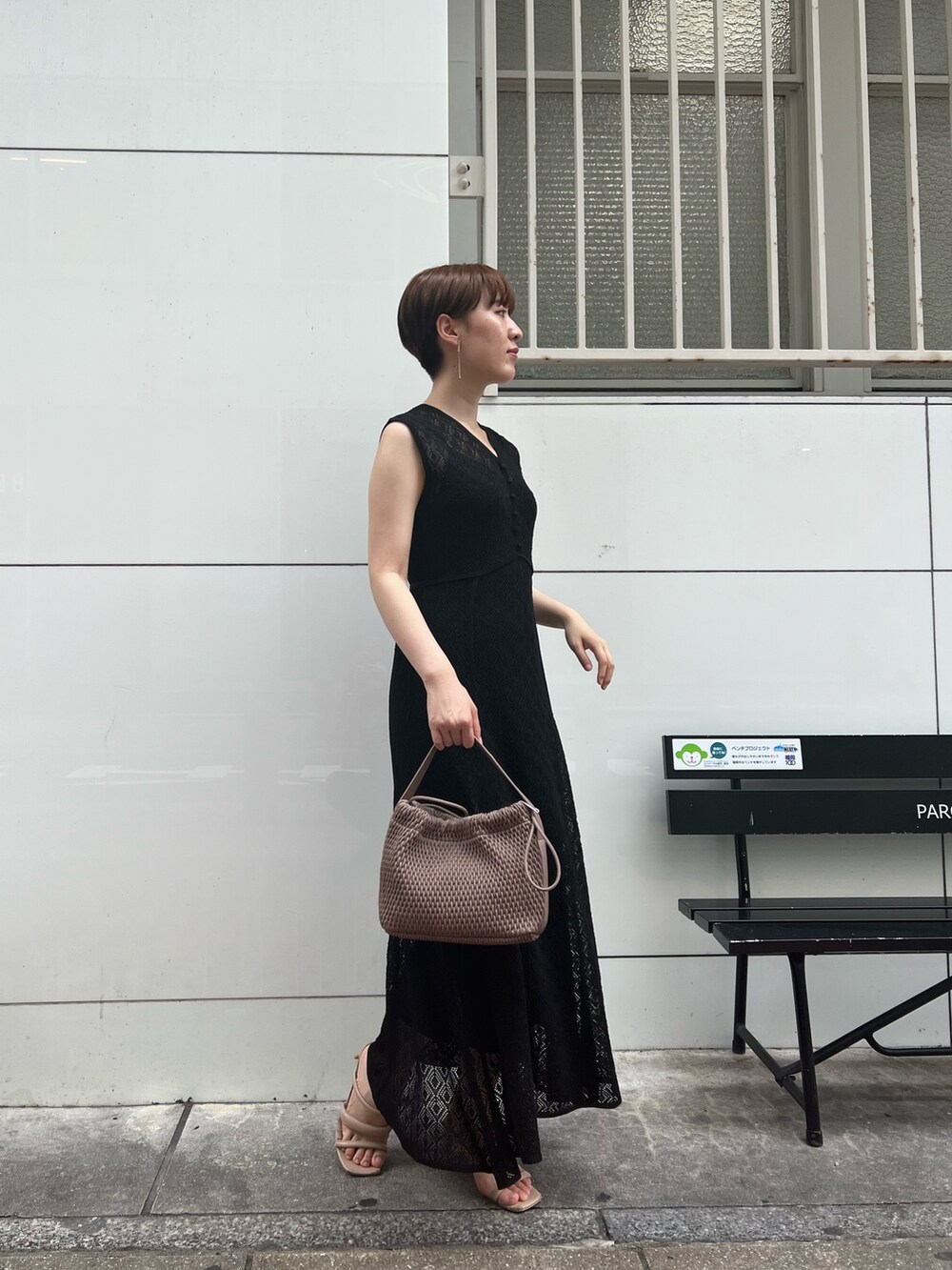 ベージュ系のサンダル、ホワイト系のハンドバッグ、ブラック系のワンピースを着用したレディースの夏コーディネートの2枚目の写真