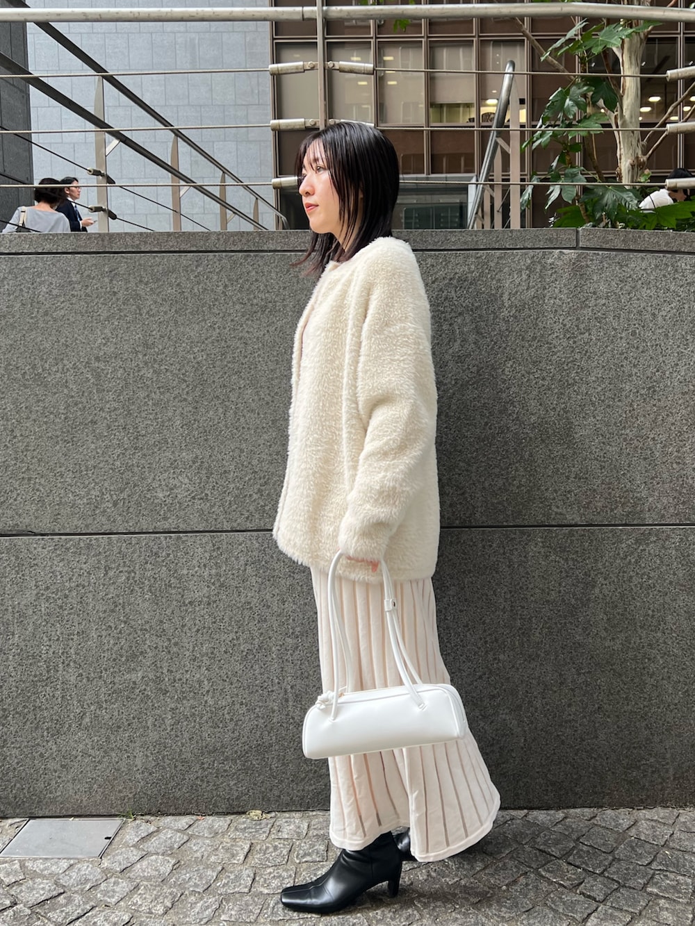 ブラック系のブーツ、ホワイト系のカーディガン/ボレロ、ホワイト系のショルダーバッグを着用したレディースの秋コーディネートの2枚目の写真