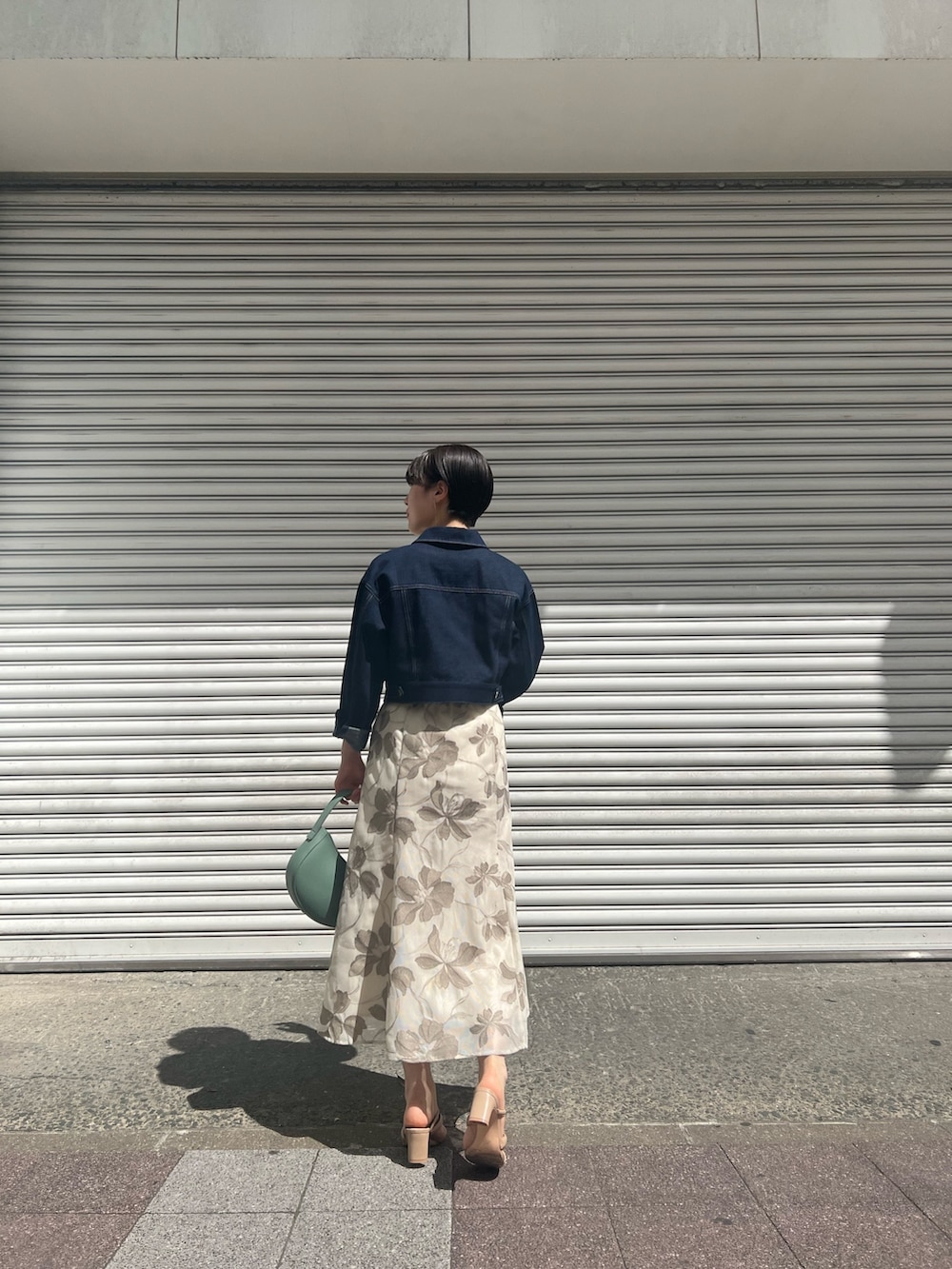 グリーン系のハンドバッグ、ホワイト系のニット/セーター、ベージュ系のサンダルを着用したレディースの春コーディネートの3枚目の写真