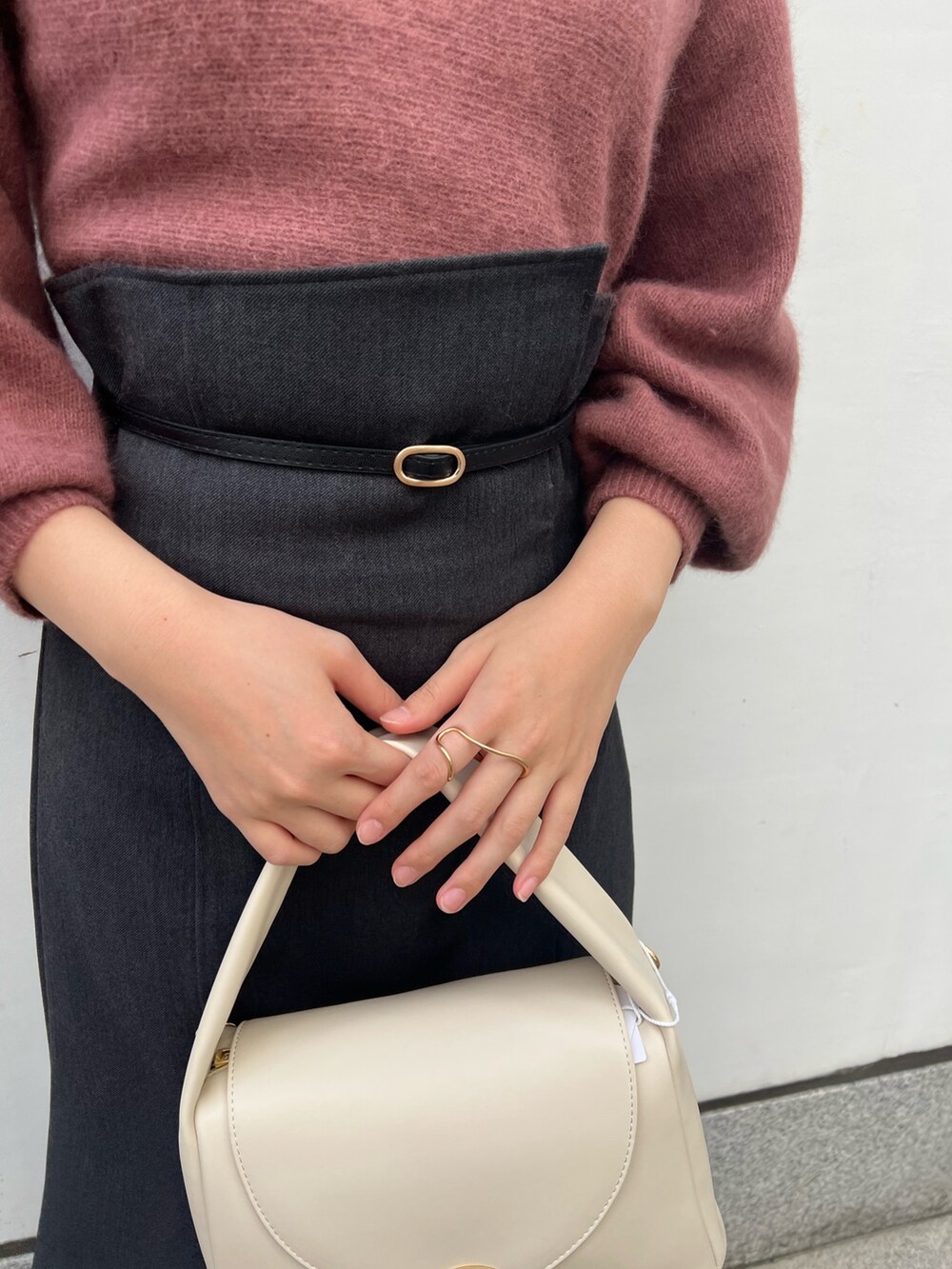 ホワイト系のハンドバッグ、グレー系のスカート、ベージュ系のブーツを着用したレディースの秋コーディネートの8枚目の写真