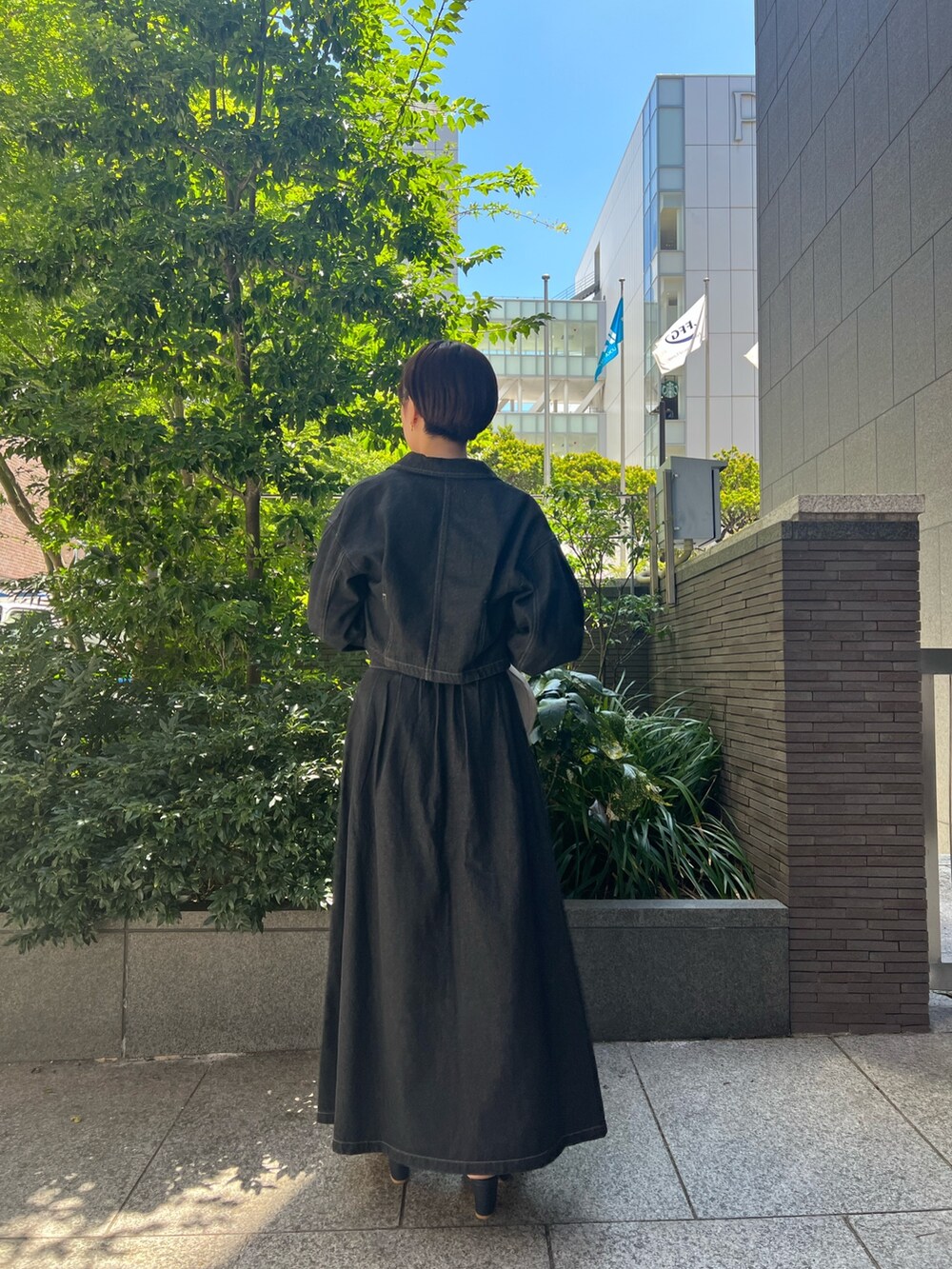 ブラック系のデニムジャケット、ブルー系のニット/セーター、ホワイト系のハンドバッグを着用したレディースの秋コーディネートの3枚目の写真