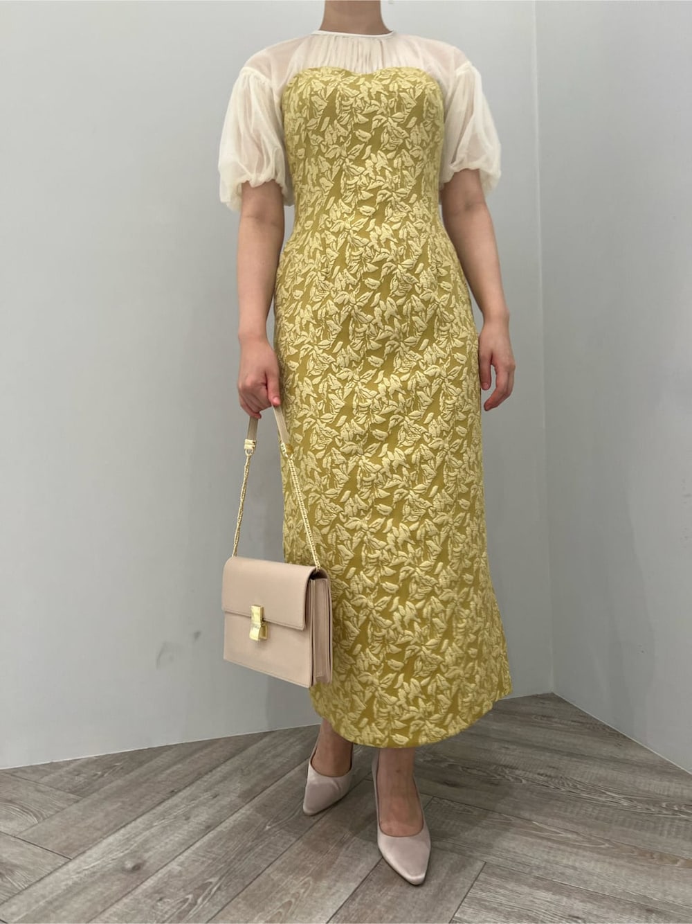 ベージュ系のパンプス、イエロー系のドレス、ベージュ系のクラッチバッグを着用したレディースの秋コーディネートの5枚目の写真