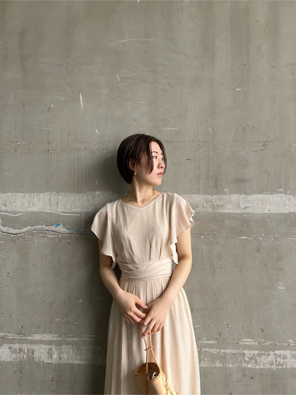 ホワイト系のワンピース、ブラウン系のパンプス、オレンジ系のショルダーバッグを着用したレディースの春コーディネートの9枚目の写真