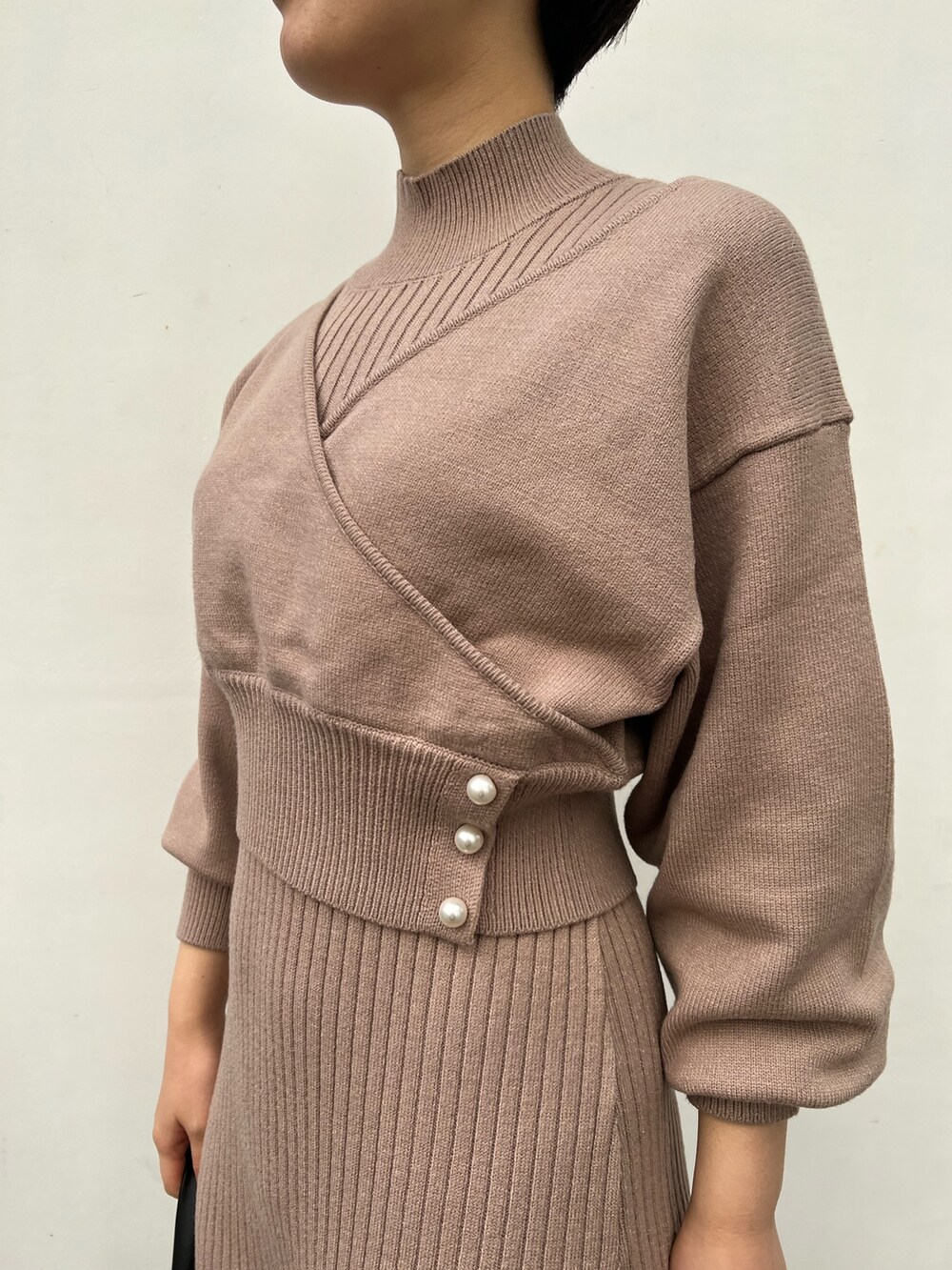 レッド系のブーツ、ブラック系のハンドバッグ、ベージュ系のワンピースを着用したレディースの冬コーディネートの7枚目の写真