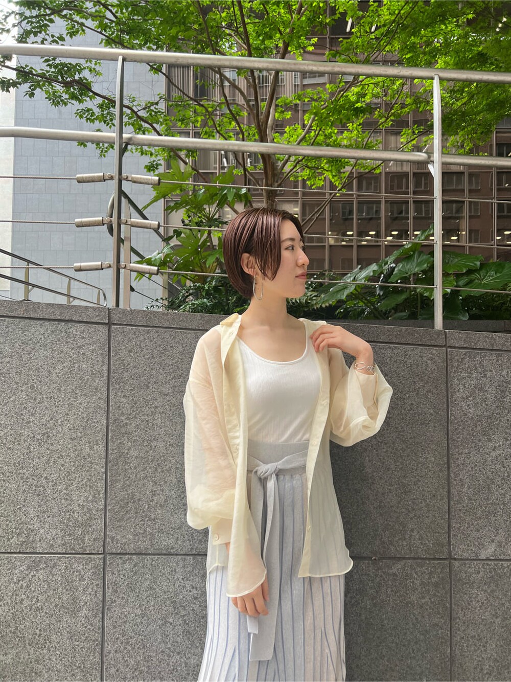 ホワイト系のシャツ/ブラウス、ブルー系のスカート、ブラウン系のパンプスを着用したレディースの春コーディネートの7枚目の写真
