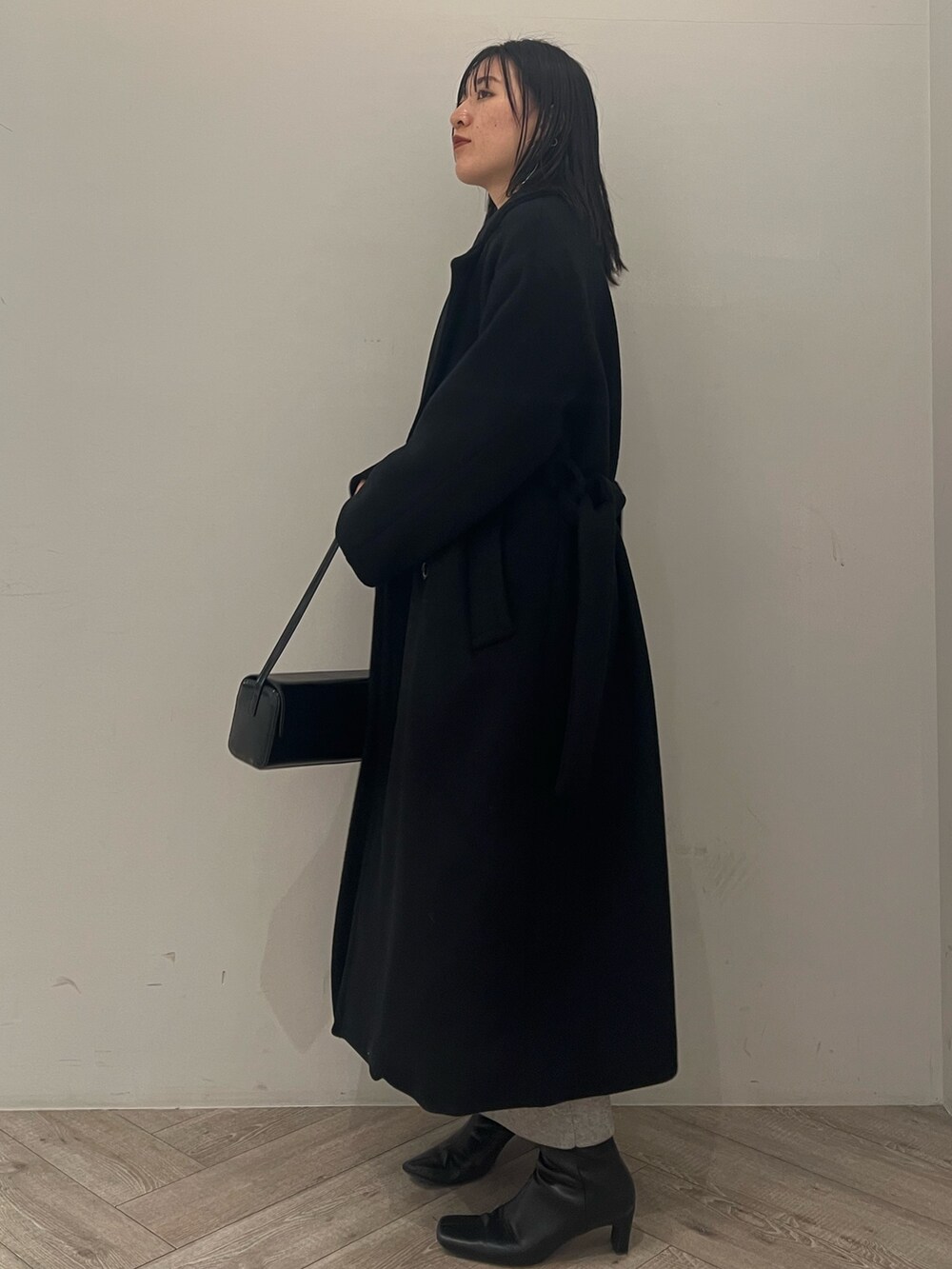 ブラック系のチェスターコートを着用したレディースの冬コーディネートの2枚目の写真