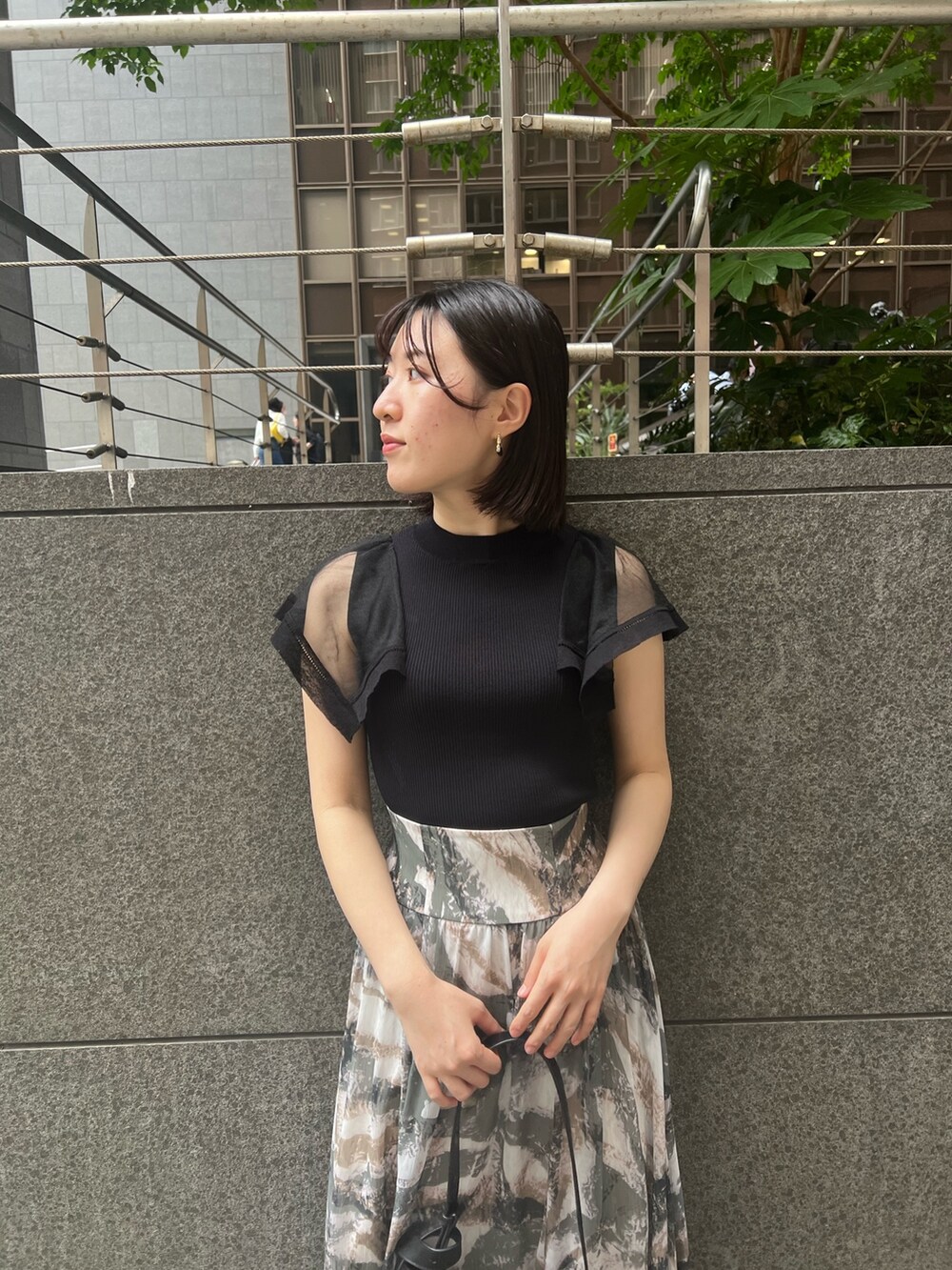 ブラック系のニット/セーター、グレー系のスカート、ブラック系のショルダーバッグを着用したレディースの春コーディネートの3枚目の写真