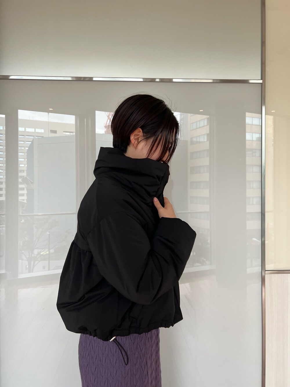 ブラック系のダウンジャケット/コート、ブラック系のブーツ、パープル系のワンピースを着用したレディースの冬コーディネートの5枚目の写真