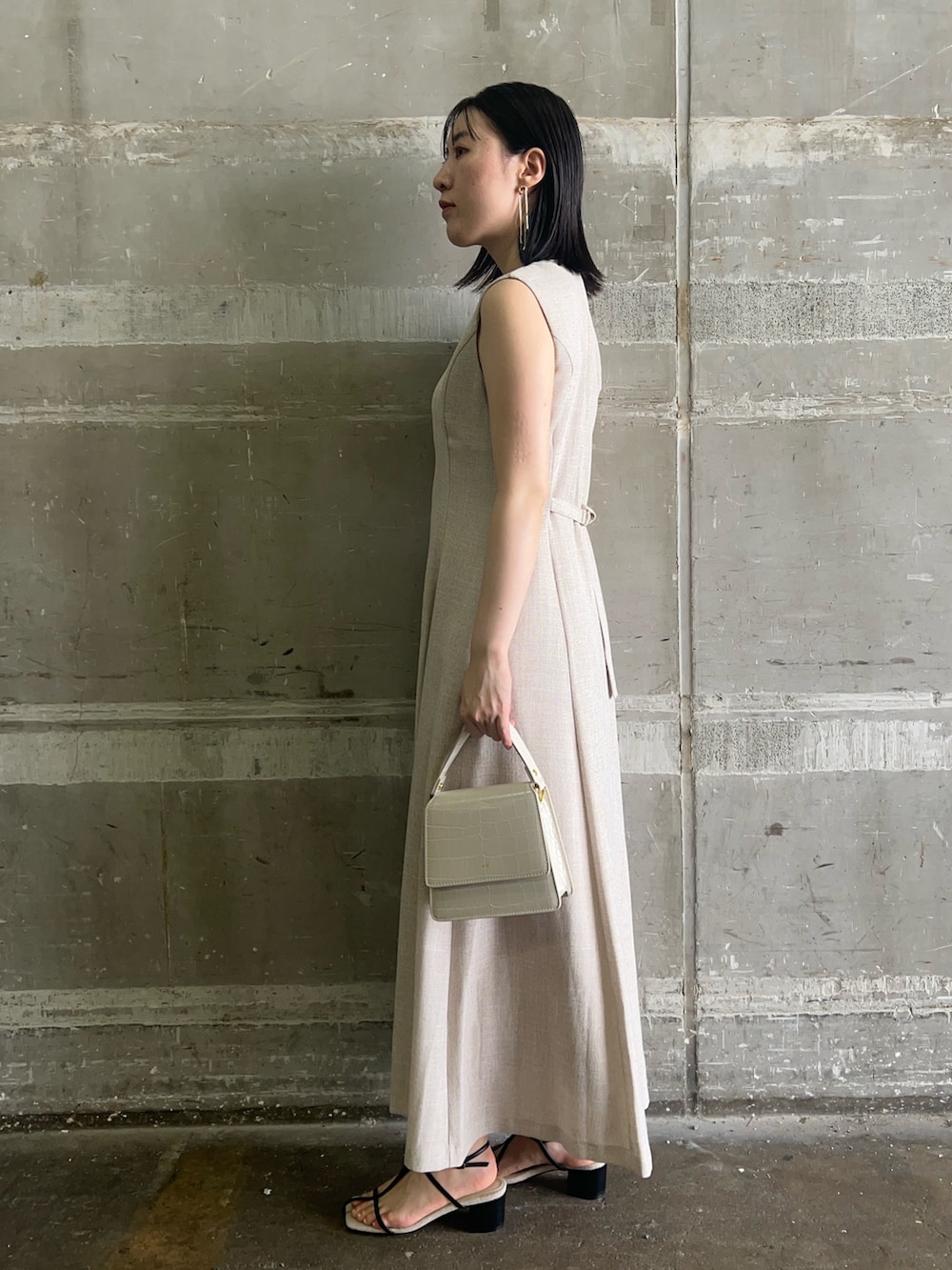 ブラック系のサンダル、ホワイト系のショルダーバッグ、ベージュ系のワンピースを着用したレディースの夏コーディネートの2枚目の写真
