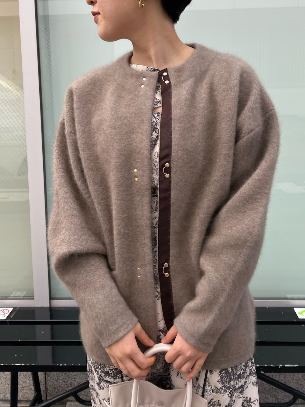 レッド系のブーツ、ホワイト系のハンドバッグ、ベージュ系のカーディガン/ボレロを着用したレディースの冬コーディネートの2枚目の写真