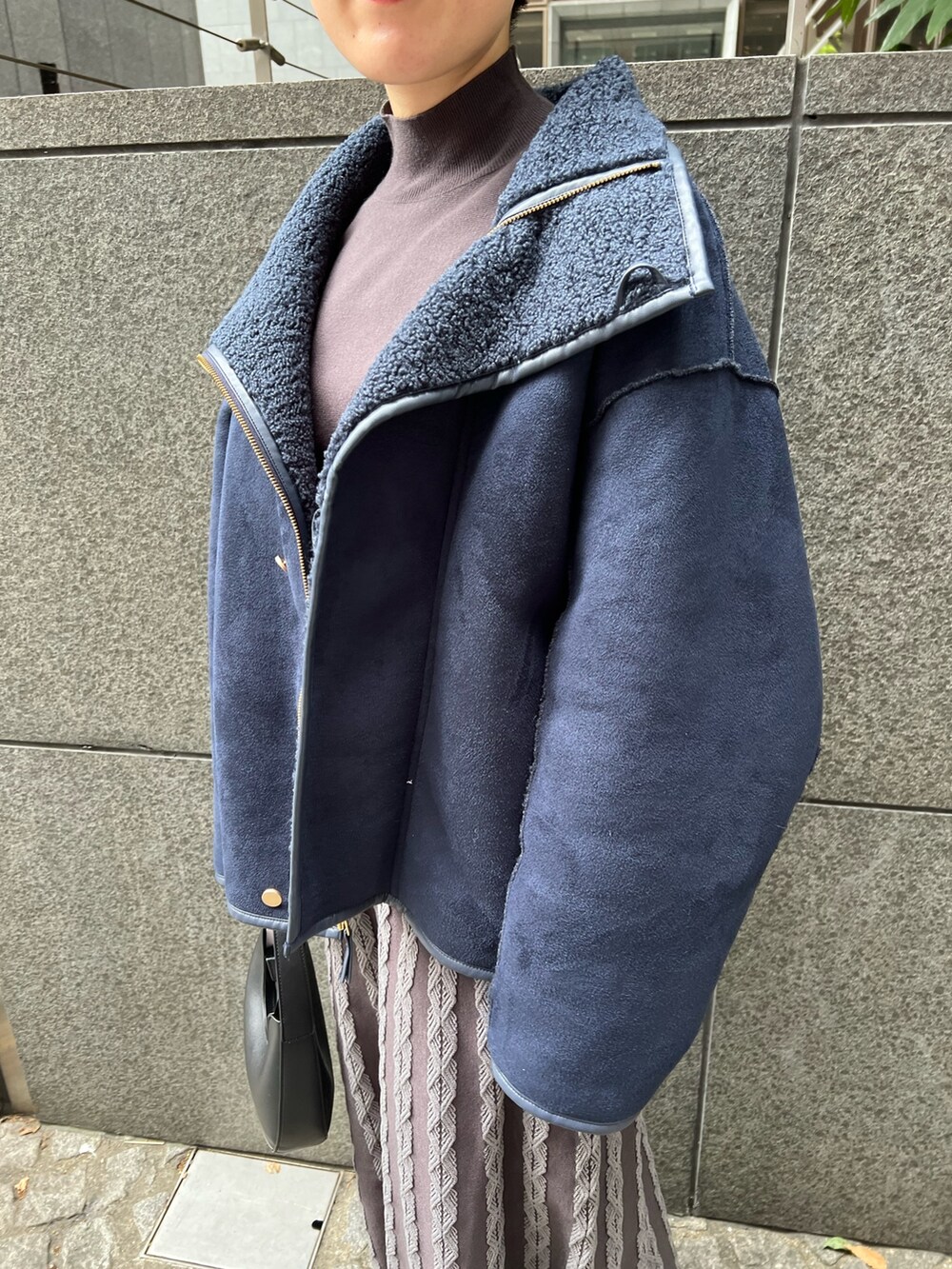 ベージュ系のブーツ、ブラック系のハンドバッグ、ブルー系のムートンコートを着用したレディースの秋コーディネートの3枚目の写真