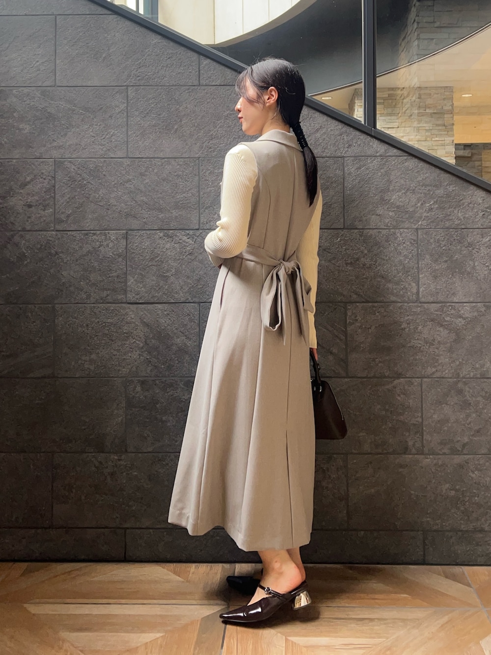 ブラウン系のパンプス、グレー系のワンピース、ホワイト系のニット/セーターを着用したレディースの秋コーディネートの2枚目の写真