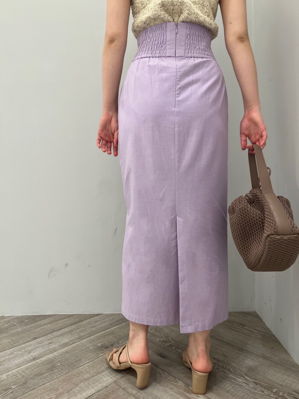 ホワイト系のハンドバッグ、ホワイト系のニット/セーター、パープル系のスカートを着用したレディースの春コーディネートの3枚目の写真