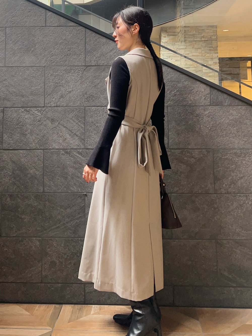 ブラック系のブーツ、ブラック系のニット/セーター、グレー系のワンピースを着用したレディースの秋コーディネートの2枚目の写真