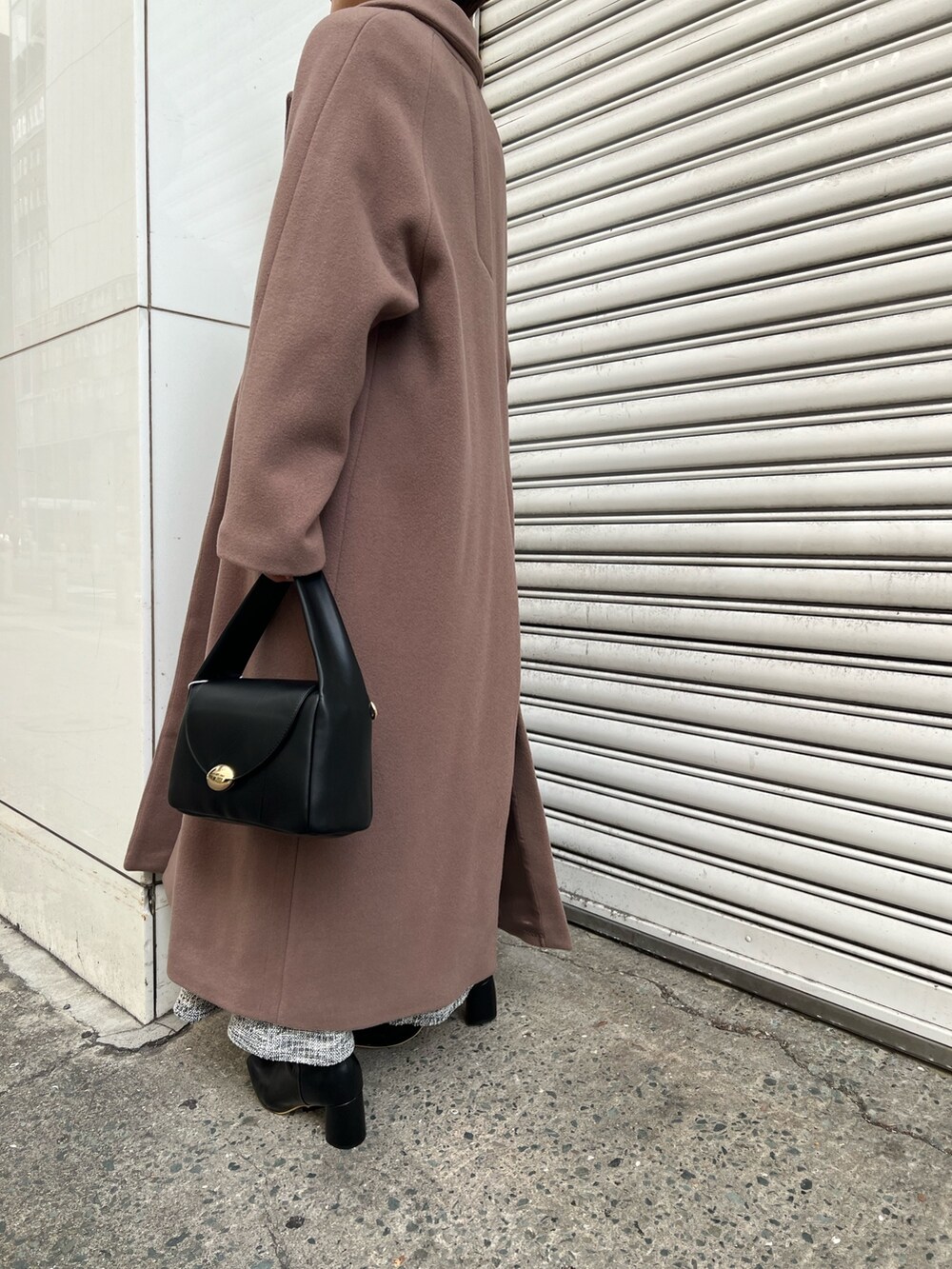ブラック系のニット/セーター、ブラウン系のチェスターコート、ブラック系のハンドバッグを着用したレディースの冬コーディネートの3枚目の写真
