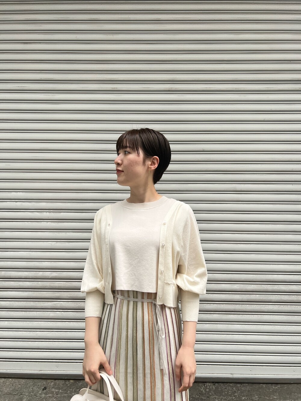 ホワイト系のショルダーバッグ、ベージュ系のサンダル、ホワイト系のワンピースを着用したレディースの春コーディネートの2枚目の写真