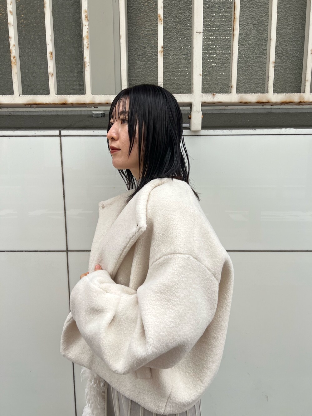 ホワイト系のブルゾン、グレー系のワンピース、ホワイト系のハンドバッグを着用したレディースの冬コーディネートの5枚目の写真