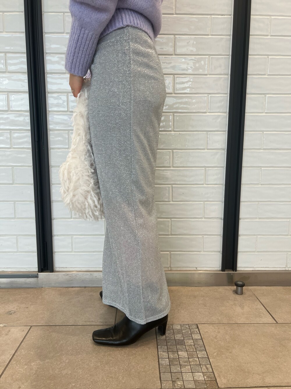 パープル系のニット/セーター、シルバー系のスカートを着用したレディースの冬コーディネートの7枚目の写真