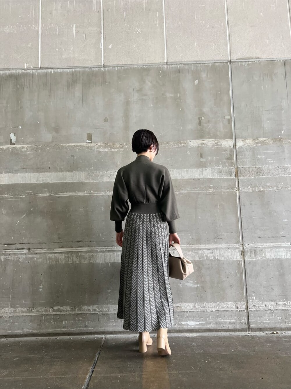 ベージュ系のブーツ、ベージュ系のハンドバッグ、ベージュ系のワンピースを着用したレディースの秋コーディネートの3枚目の写真