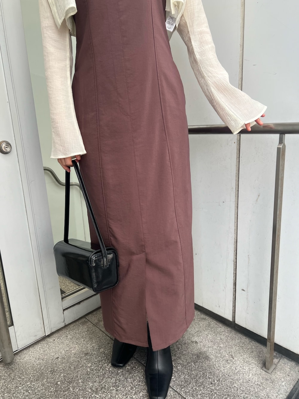 ブラック系のショルダーバッグ、ブラウン系のワンピース、ブラック系のブーツを着用したレディースの秋コーディネートの5枚目の写真