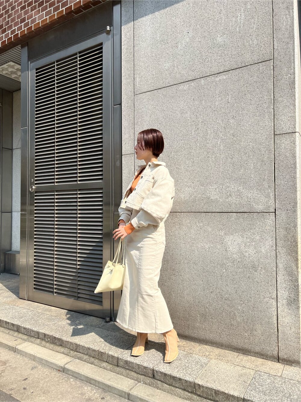 ホワイト系のブルゾン、ホワイト系のスカート、ホワイト系のハンドバッグを着用したレディースの春コーディネートの2枚目の写真