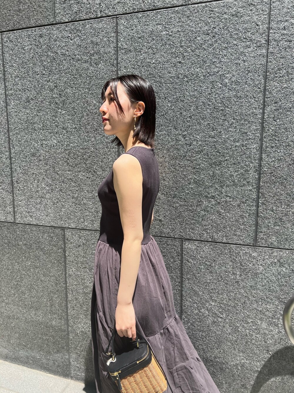 ブラック系のショルダーバッグ、ブラック系のサンダル、グレー系のワンピースを着用したレディースの春コーディネートの4枚目の写真