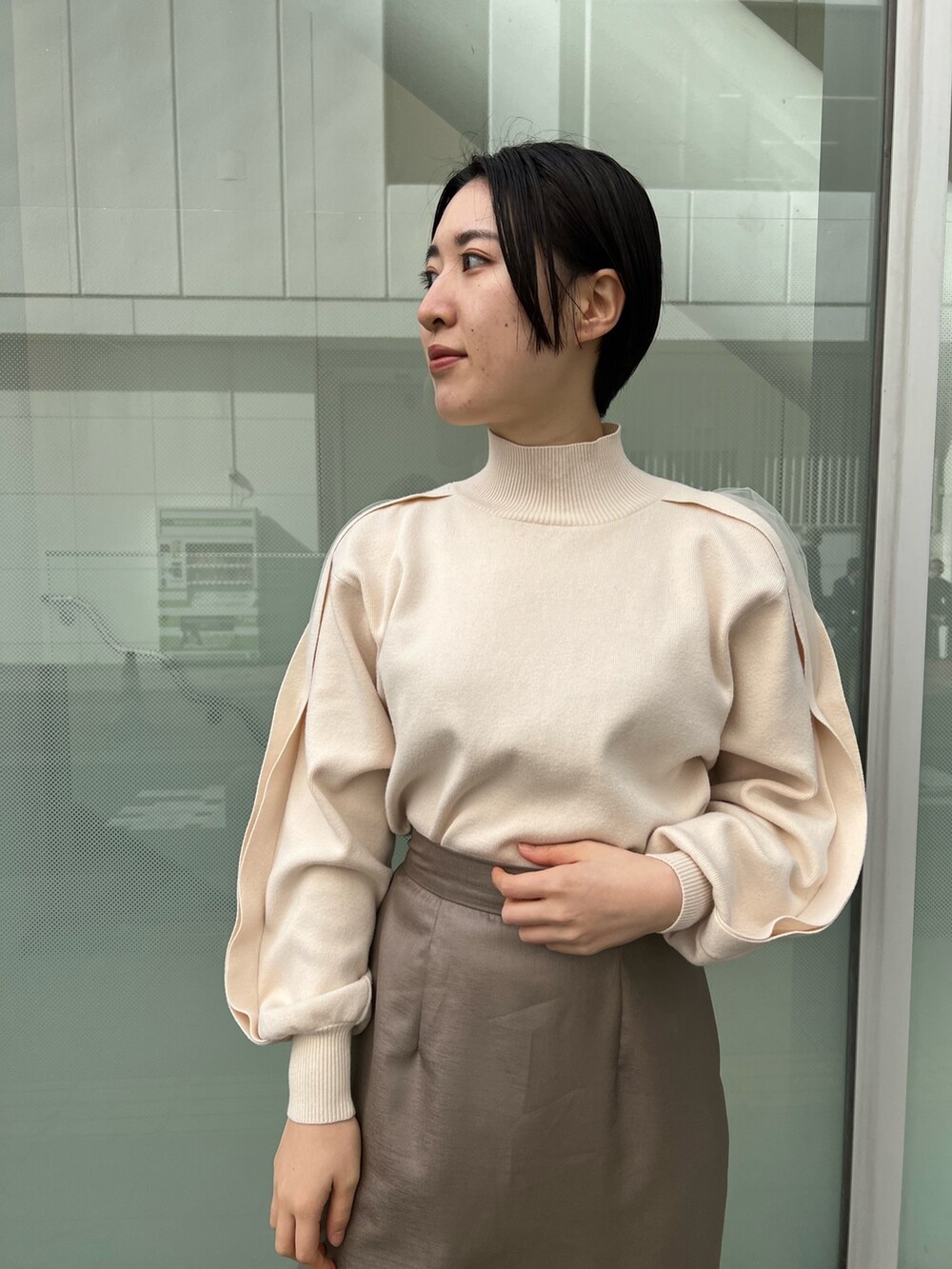 レッド系のブーツ、ベージュ系のスカート、ホワイト系のニット/セーターを着用したレディースの冬コーディネートの4枚目の写真