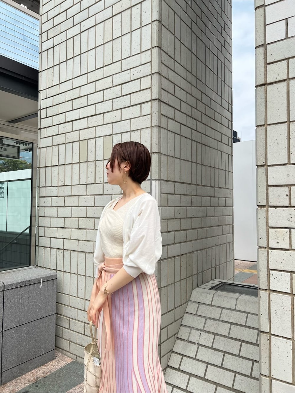 オレンジ系のスカート、その他のパンプス、ホワイト系のショルダーバッグを着用したレディースの春コーディネートの2枚目の写真