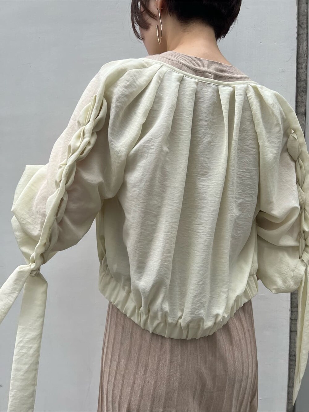 ベージュ系のハンドバッグ、ホワイト系のブルゾン、ベージュ系のワンピースを着用したレディースの春コーディネートの7枚目の写真