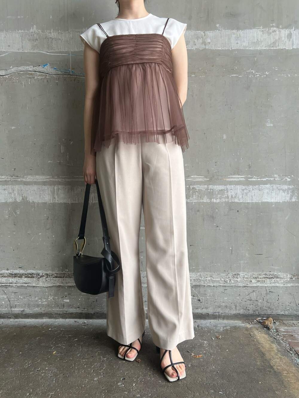 ブラック系のサンダル、ブラック系のショルダーバッグ、ホワイト系のスラックスを着用したレディースの夏コーディネートの7枚目の写真