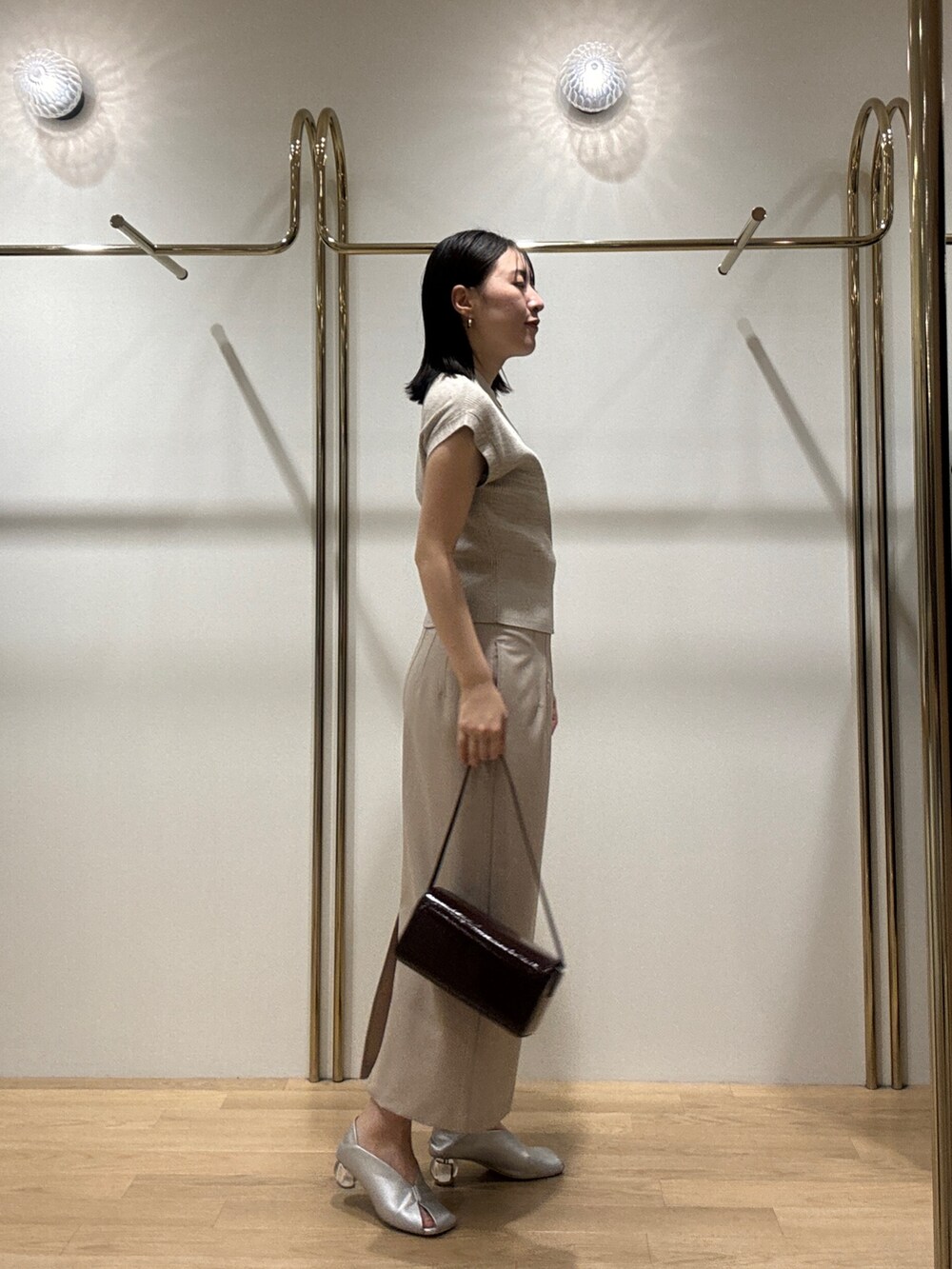 シルバー系のパンプス、ベージュ系のニット/セーター、レッド系のショルダーバッグを着用したレディースの秋コーディネートの2枚目の写真