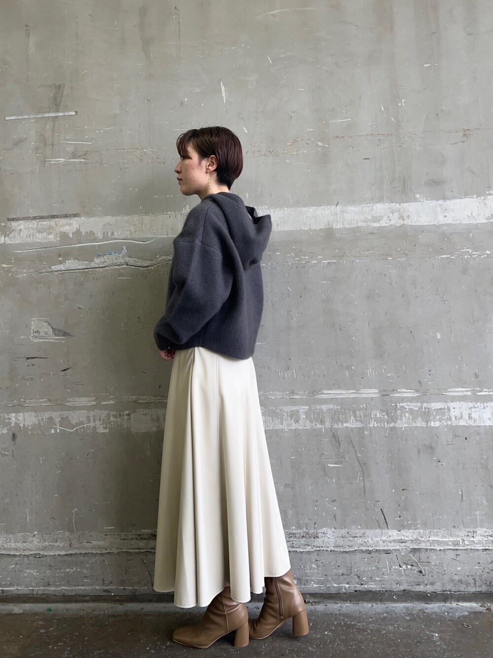 ベージュ系のブーツ、グレー系のパーカー、ホワイト系のスカートを着用したレディースの秋コーディネートの2枚目の写真