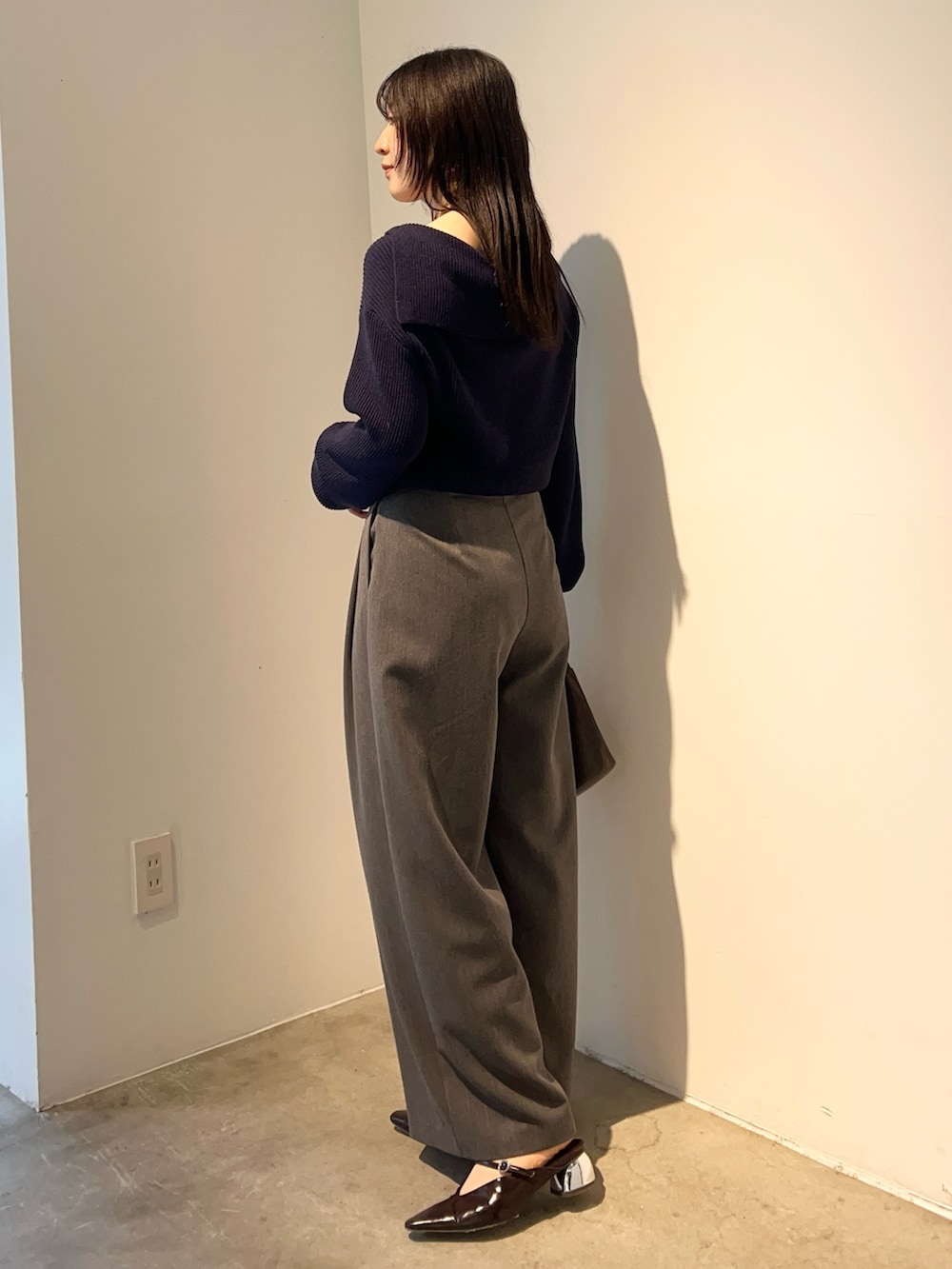 イエロー系のハンドバッグ、ブルー系のニット/セーター、ブラウン系のパンプスを着用したレディースの秋コーディネートの2枚目の写真