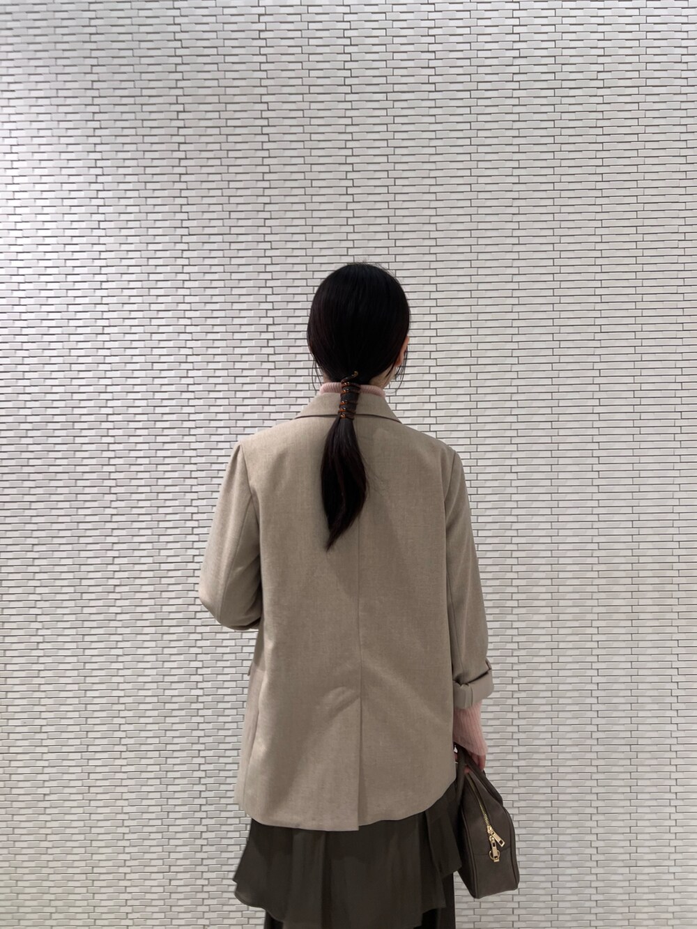 ピンク系のニット/セーター、ブラック系のブーツ、ベージュ系のテーラードジャケットを着用したレディースの秋コーディネートの6枚目の写真