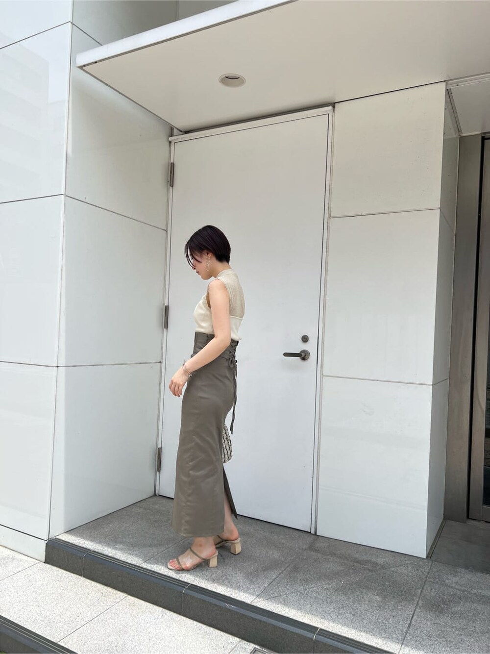 グリーン系のサンダル、ベージュ系のスカート、ホワイト系のニット/セーターを着用したレディースの夏コーディネートの3枚目の写真