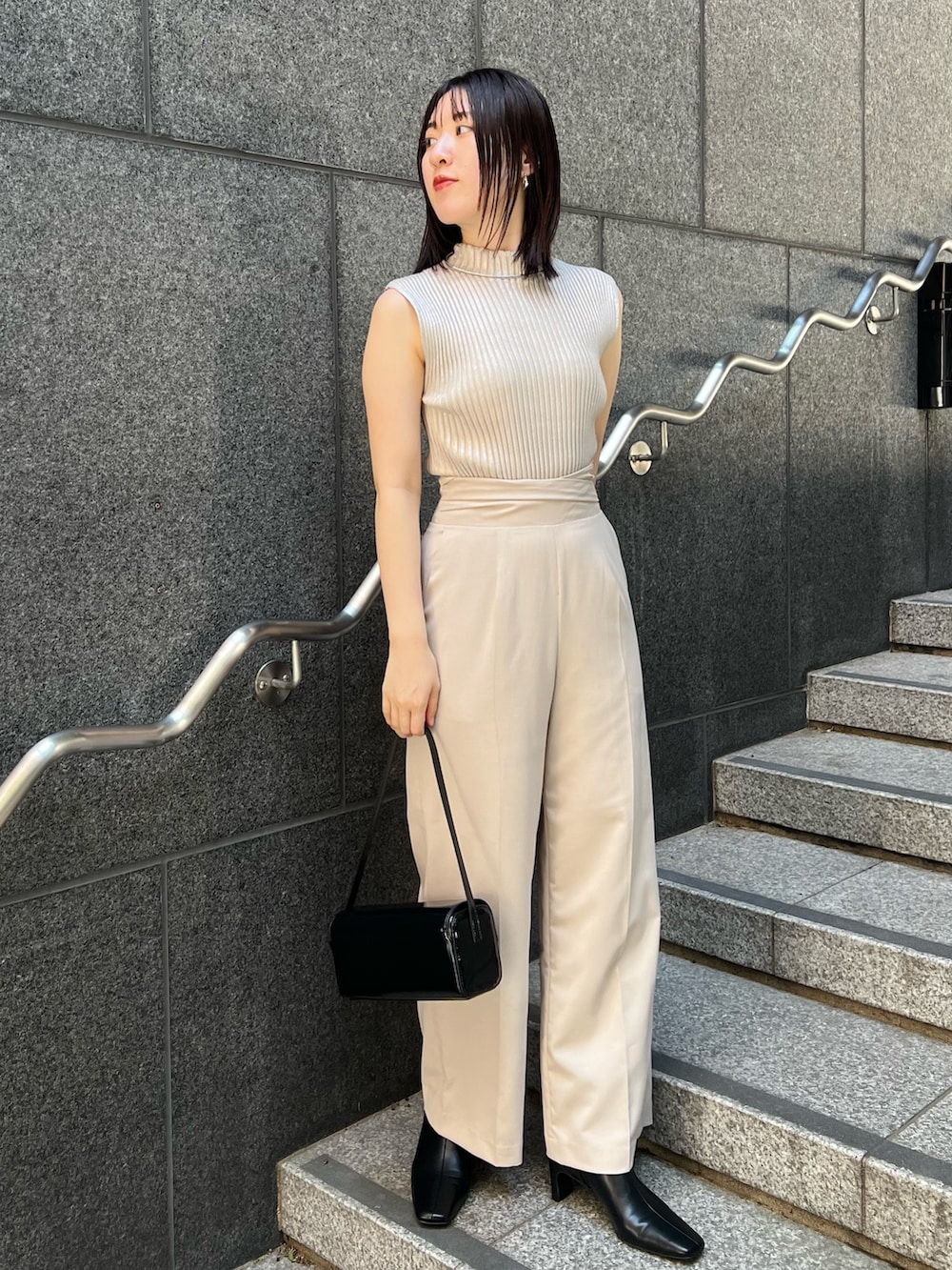 ブラック系のショルダーバッグ、ブラック系のブーツ、ホワイト系のスラックスを着用したレディースの秋コーディネートの2枚目の写真