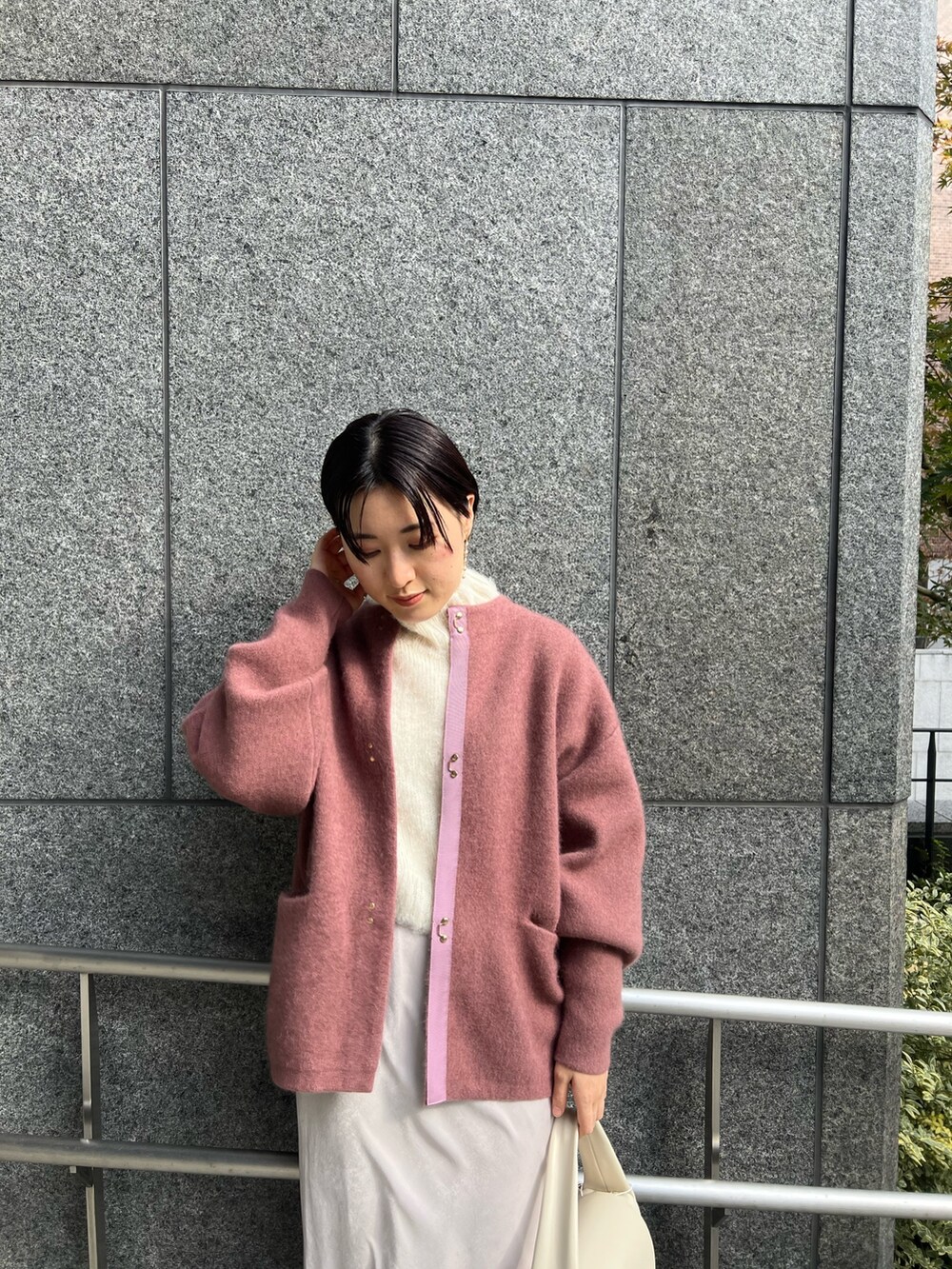 ホワイト系のスカート、ホワイト系のハンドバッグ、ピンク系のカーディガン/ボレロを着用したレディースの冬コーディネートの5枚目の写真