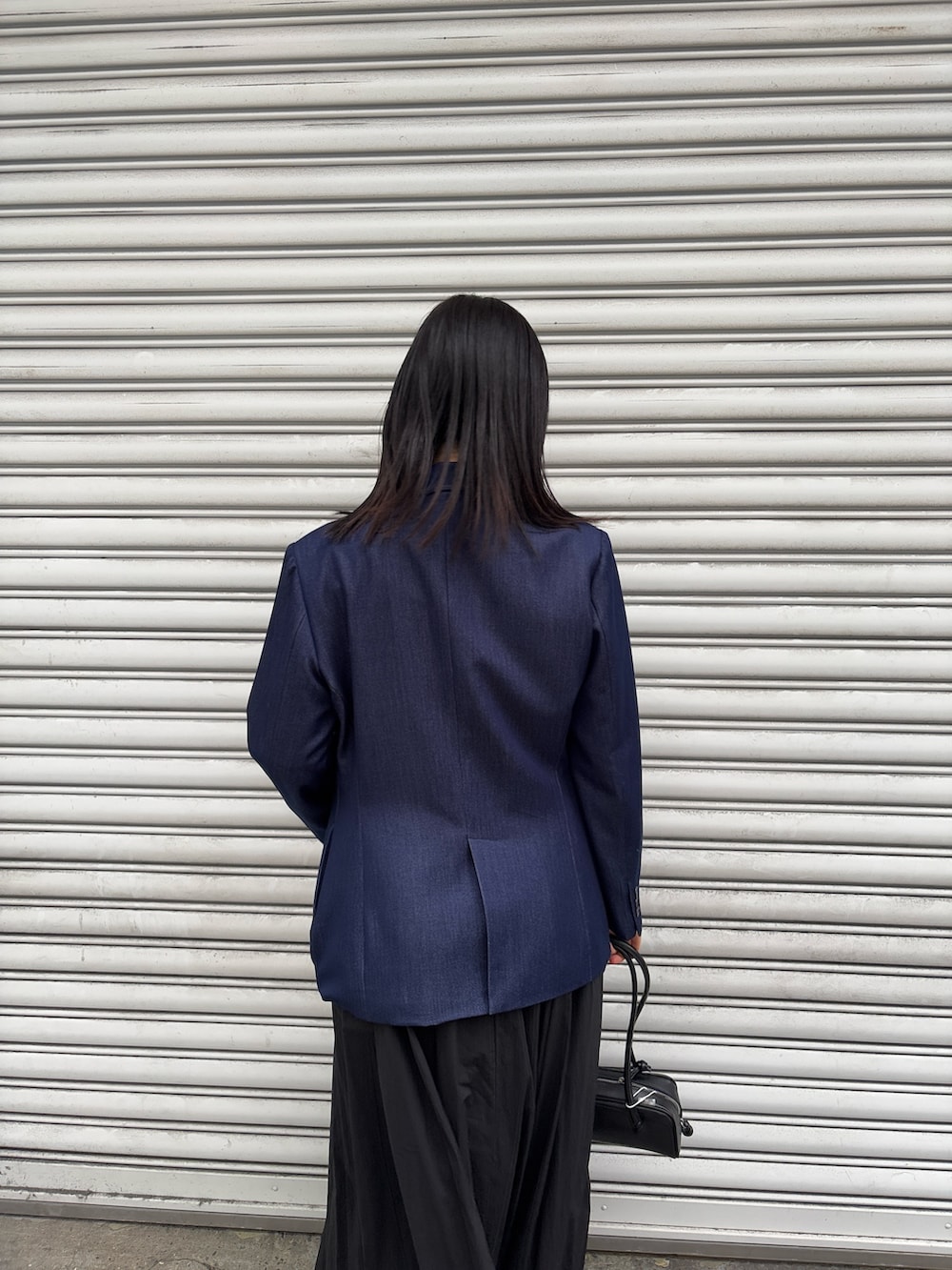 ブラック系のワンピース、ブルー系のテーラードジャケット、グレー系のスニーカーを着用したレディースの冬コーディネートの4枚目の写真