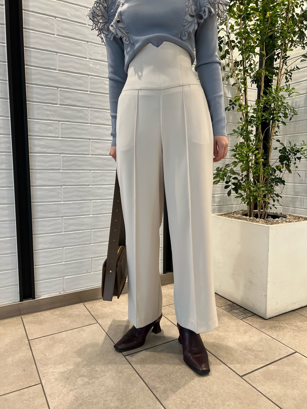 ベージュ系のノーカラーコート、ベージュ系のショルダーバッグ、レッド系のブーツを着用したレディースの冬コーディネートの9枚目の写真