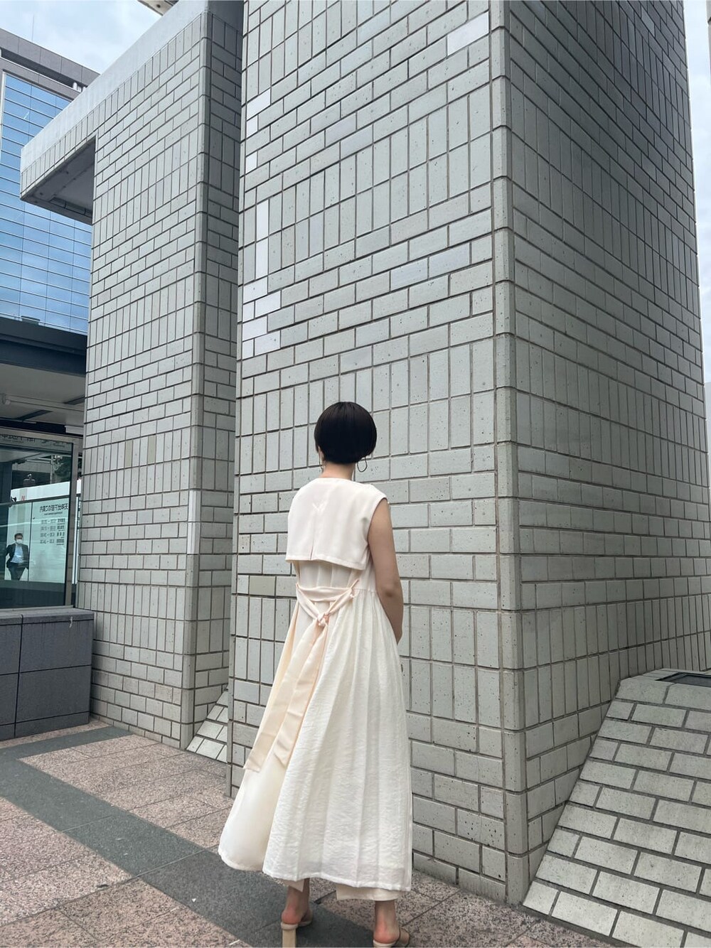 ホワイト系のハンドバッグ、ホワイト系のワンピース、グリーン系のサンダルを着用したレディースの春コーディネートの3枚目の写真