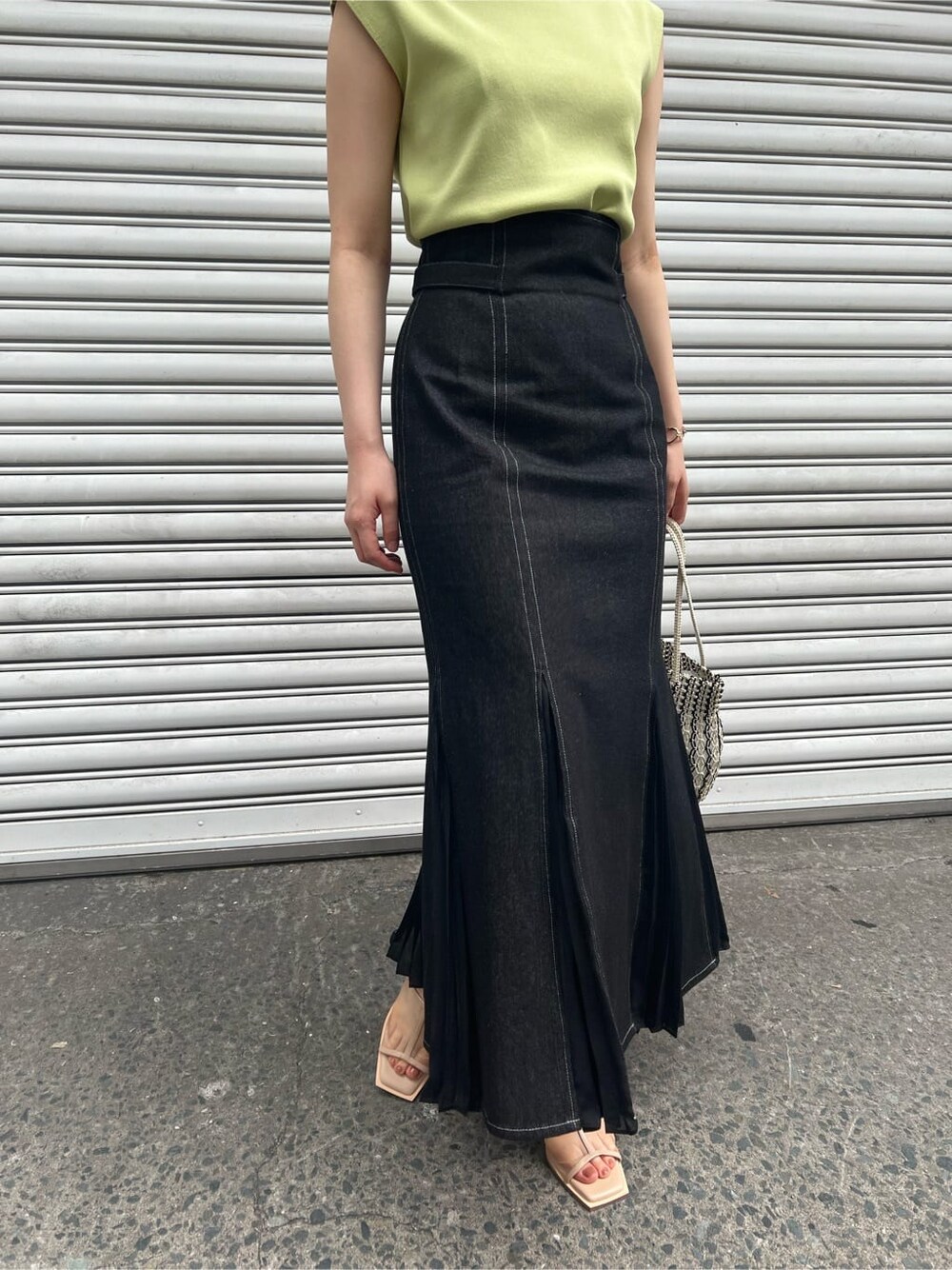 ブルー系のスカート、ベージュ系のサンダル、イエロー系のニット/セーターを着用したレディースの春コーディネートの8枚目の写真