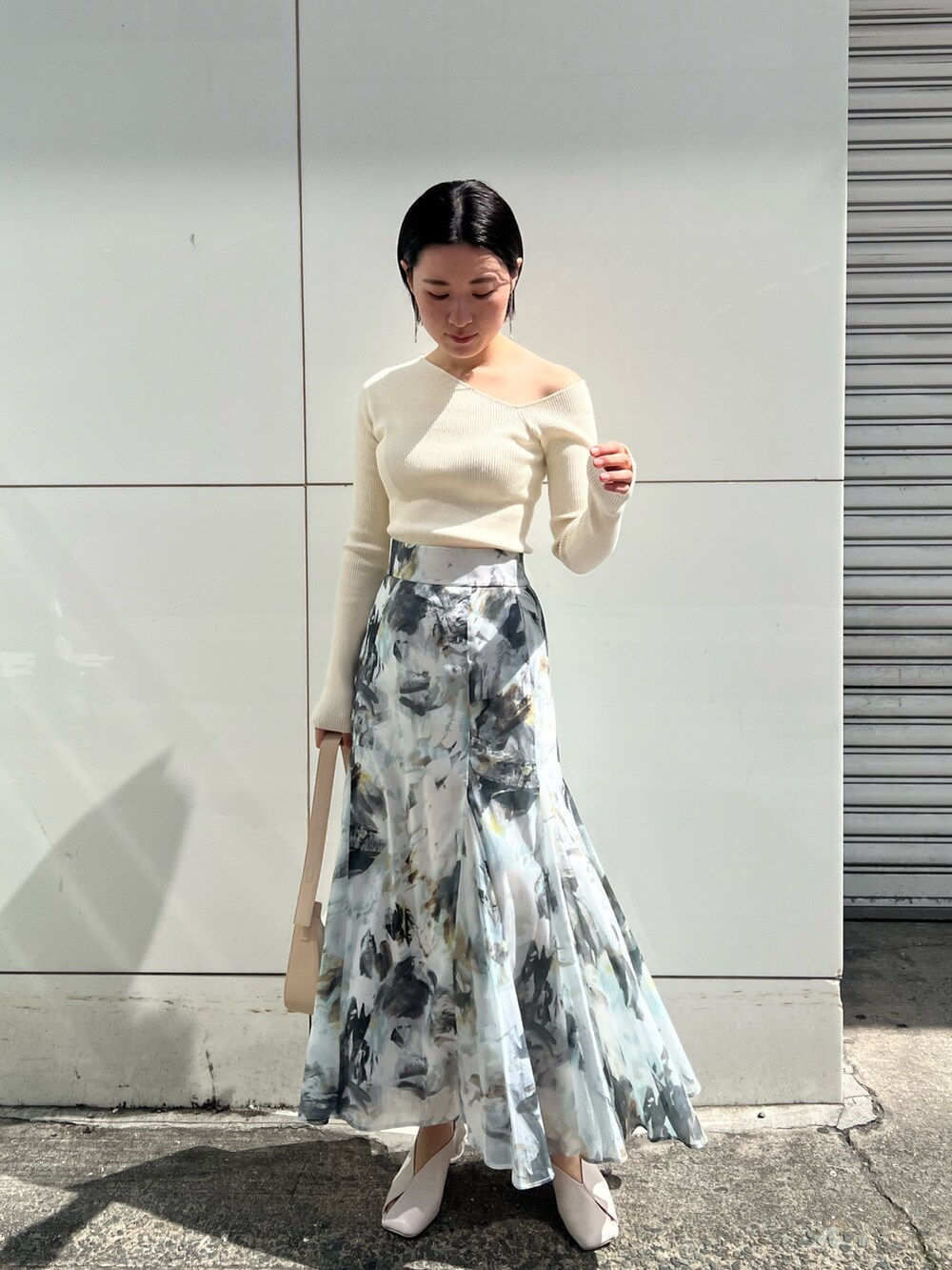 ホワイト系のパンプス、ベージュ系のハンドバッグ、ホワイト系のニット/セーターを着用したレディースの春コーディネートの6枚目の写真