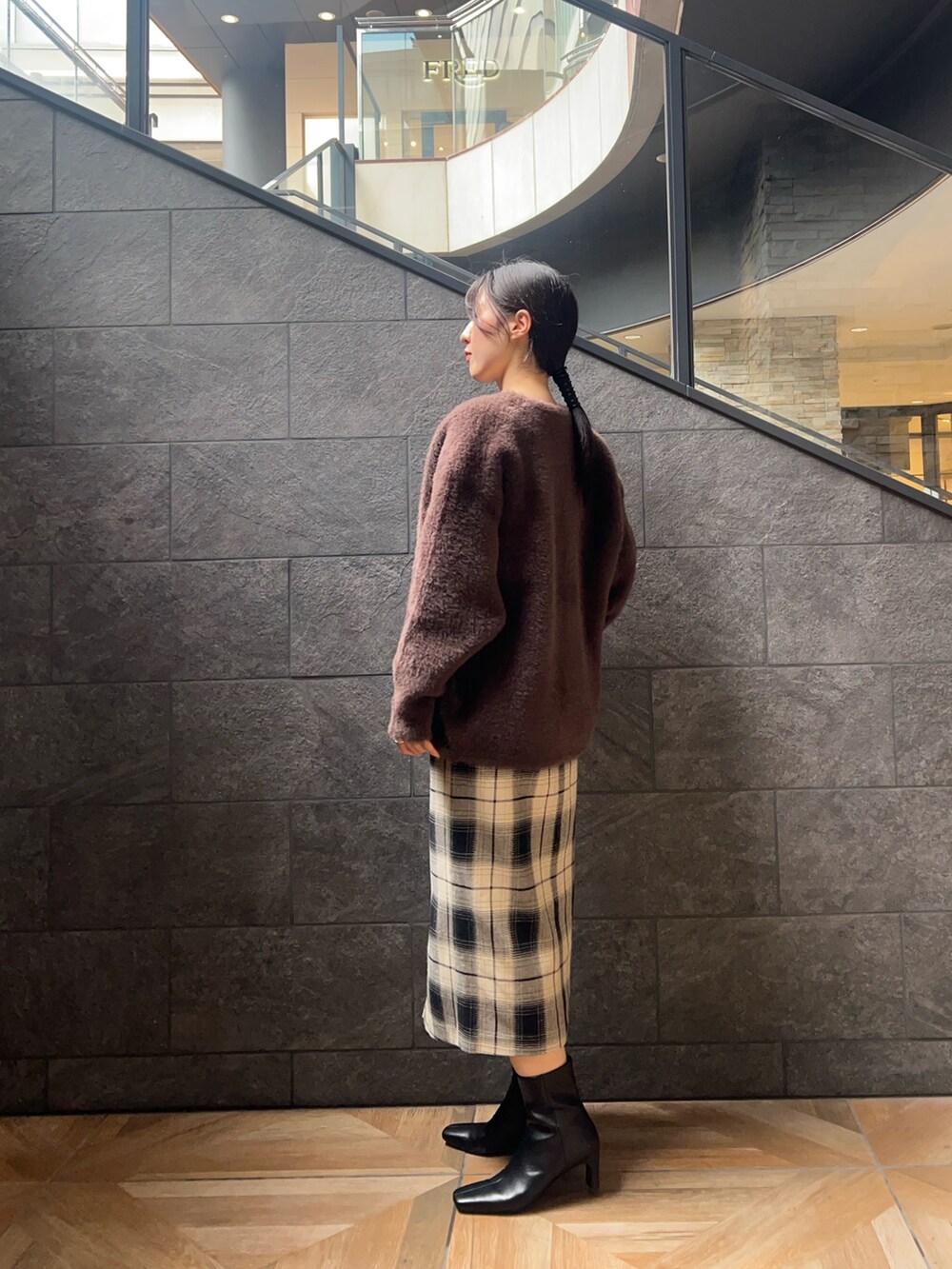 ベージュ系のスカート、ブラック系のニット/セーター、ブラウン系のカーディガン/ボレロを着用したレディースの秋コーディネートの2枚目の写真