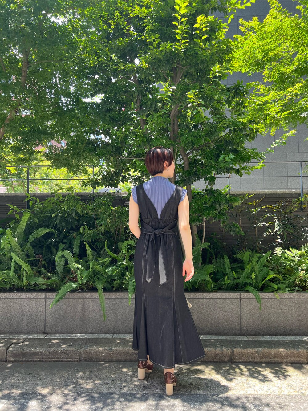 ブルー系のニット/セーター、ブラック系のワンピース、ベージュ系のハンドバッグを着用したレディースの夏コーディネートの3枚目の写真