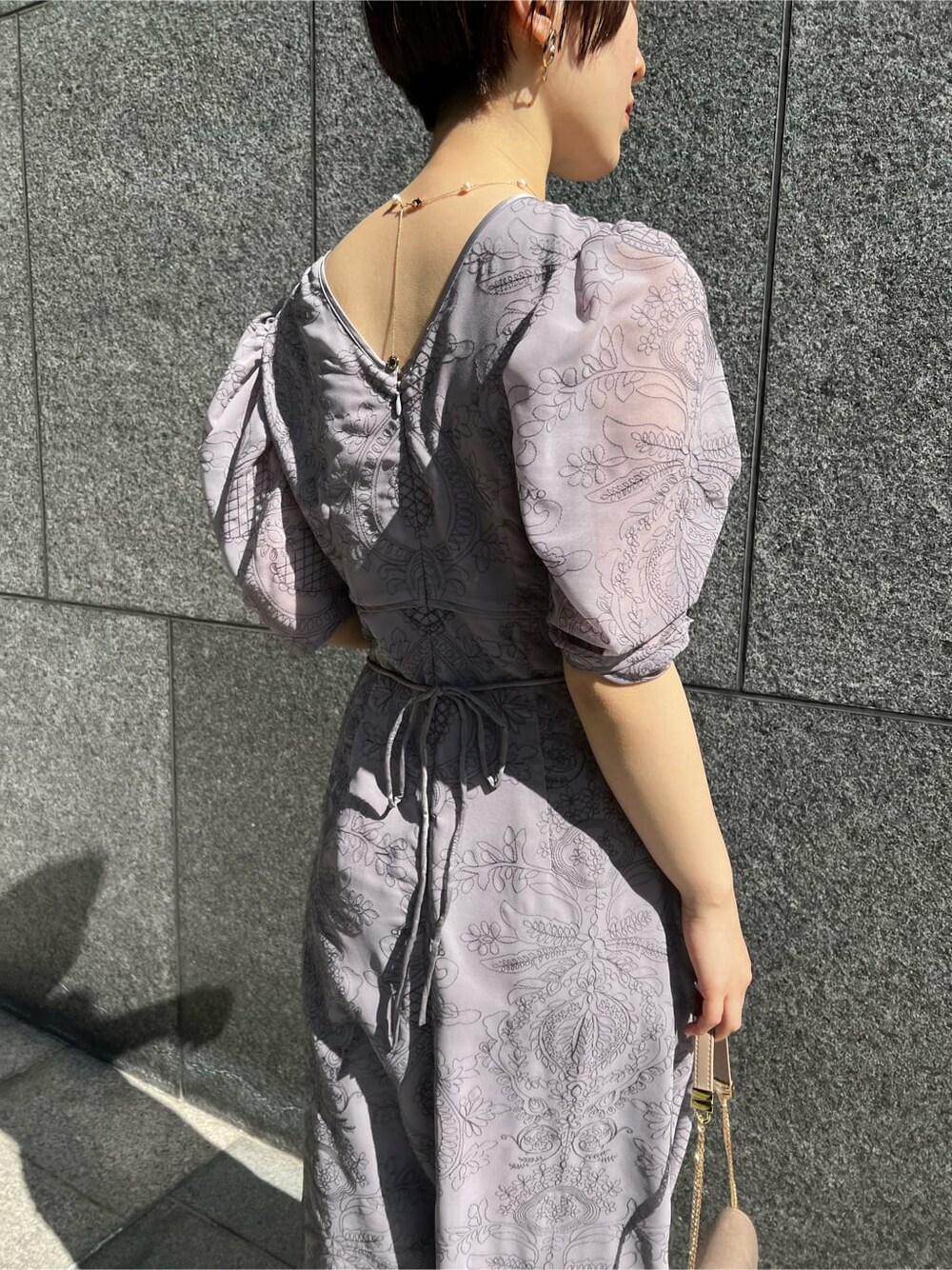 ブラウン系のクラッチバッグ、ベージュ系のその他アウター、パープル系のドレスを着用したレディースの冬コーディネートの7枚目の写真