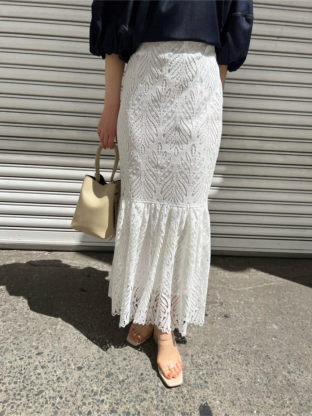 ホワイト系のハンドバッグ、ブルー系のシャツ/ブラウス、ホワイト系のスカートを着用したレディースの春コーディネートの7枚目の写真